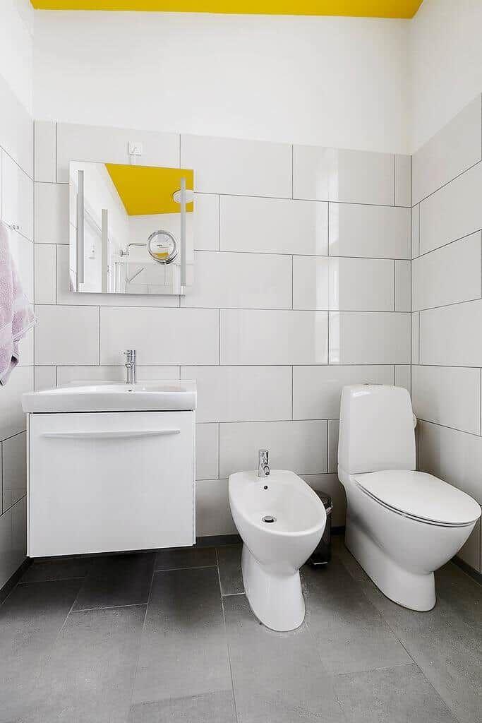Badezimmer mit weißer Wandfliese, Spiegelschrank, Bidet und Toilette.