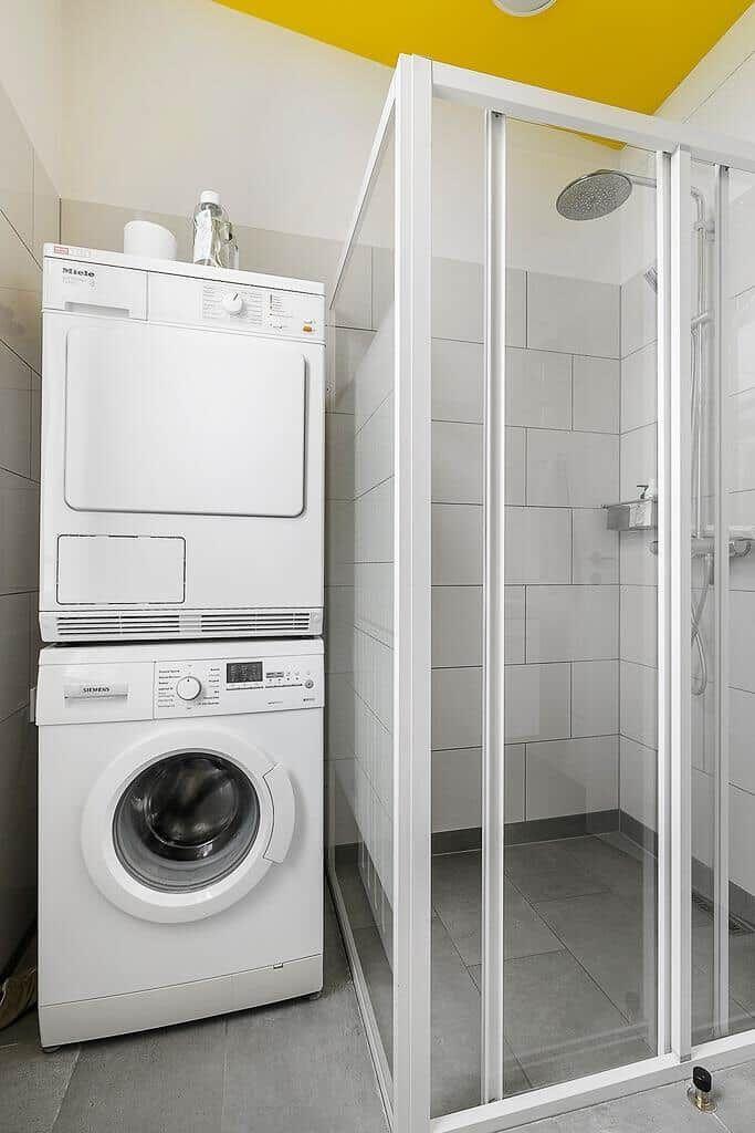 Waschmaschine und Trockner stehen neben Dusche.