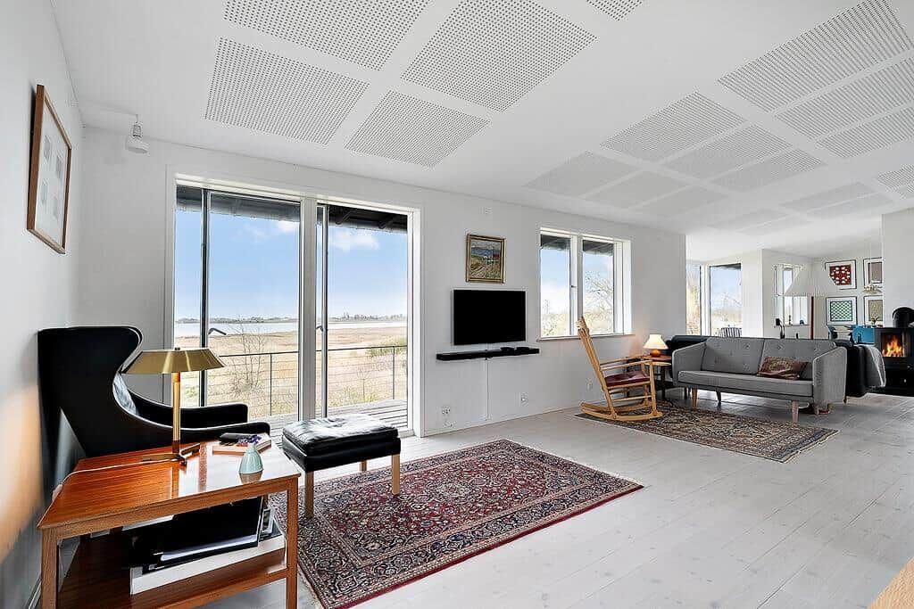 Wohnzimmer mit Sofa, Fernseher und Blick auf Felder.