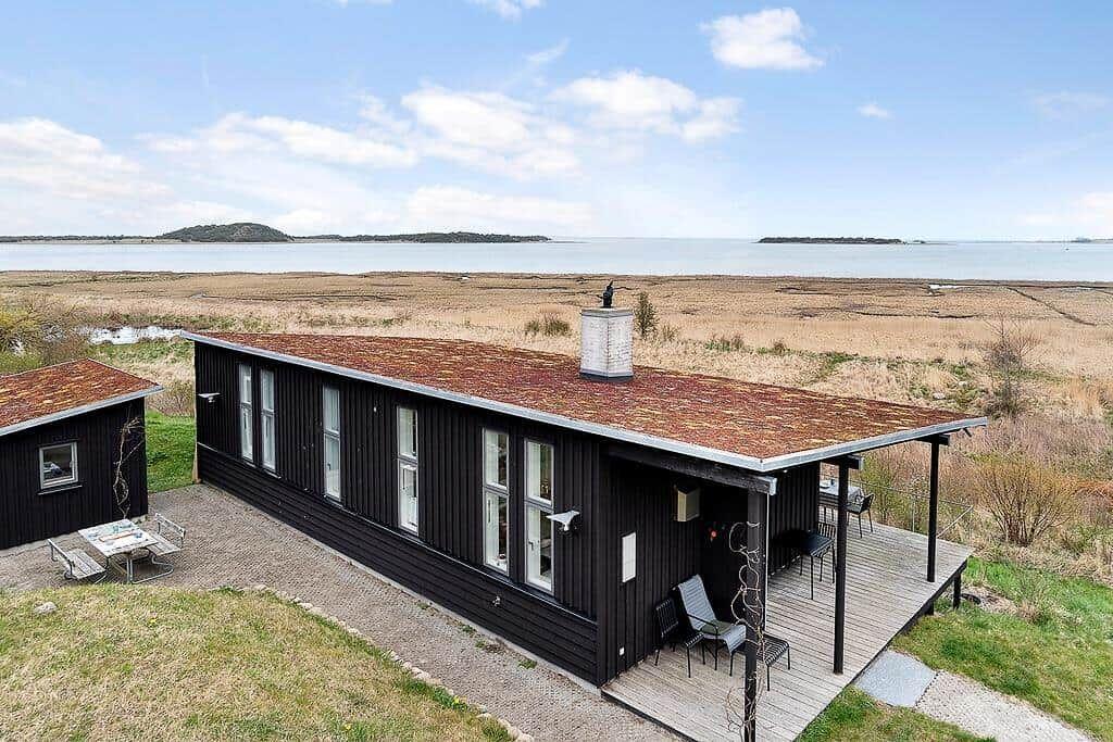 Schwarzes Haus mit Terrasse und Blick auf Wasser und Inseln.