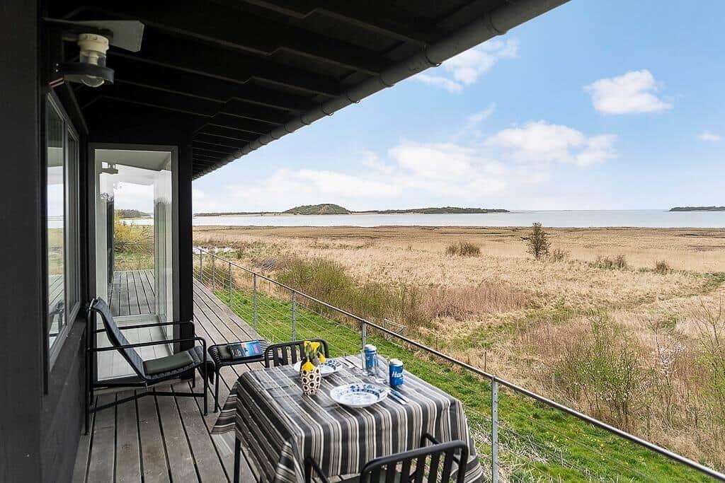 Terrasse mit Tisch und Stühlen bietet Blick auf Fluss und Insel.