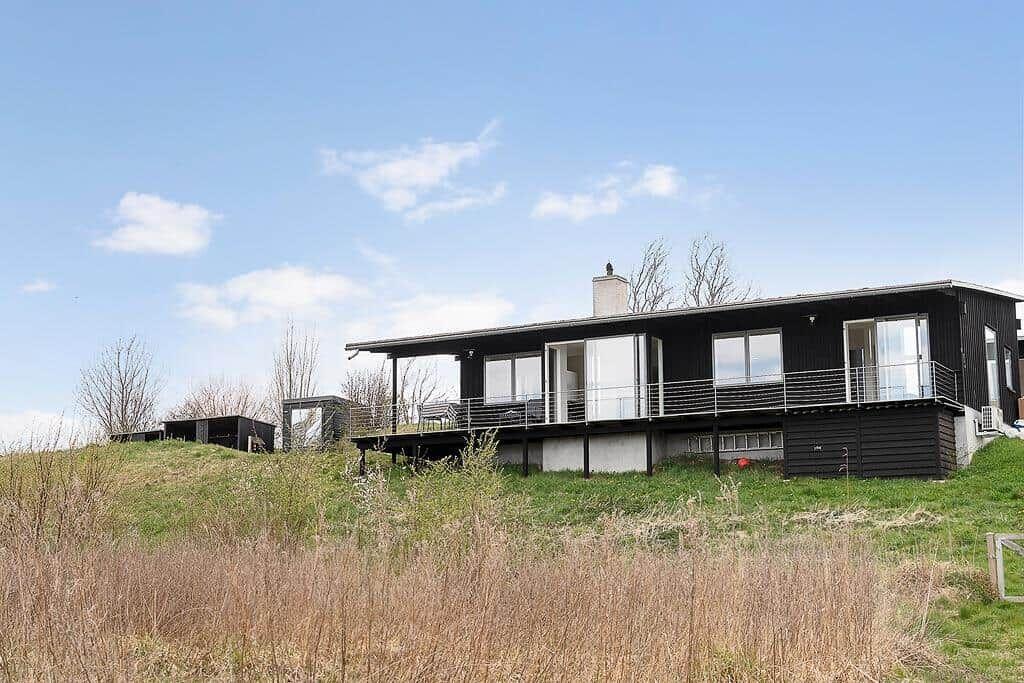 Moderne schwarze Villa mit Terrasse und großem Fensterbereich auf grüner Wiese.