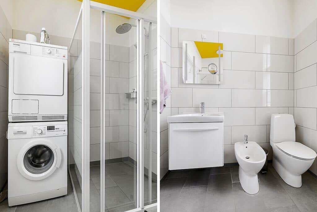 Badezimmer mit Dusche, Waschbecken, Toilette und Waschmaschine.