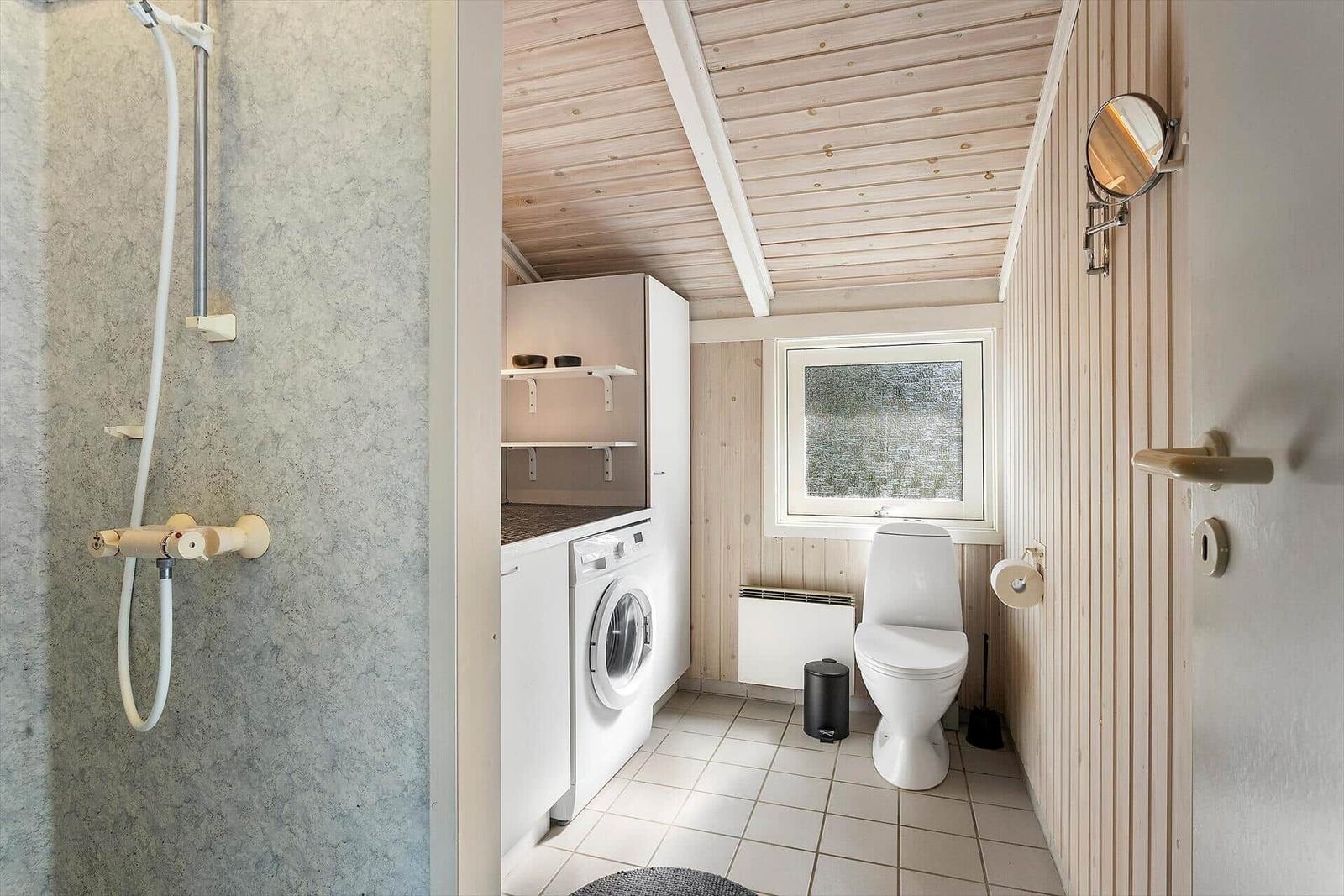 Bad mit Dusche, Waschmaschine und Toilette. Holzwände und -decke.