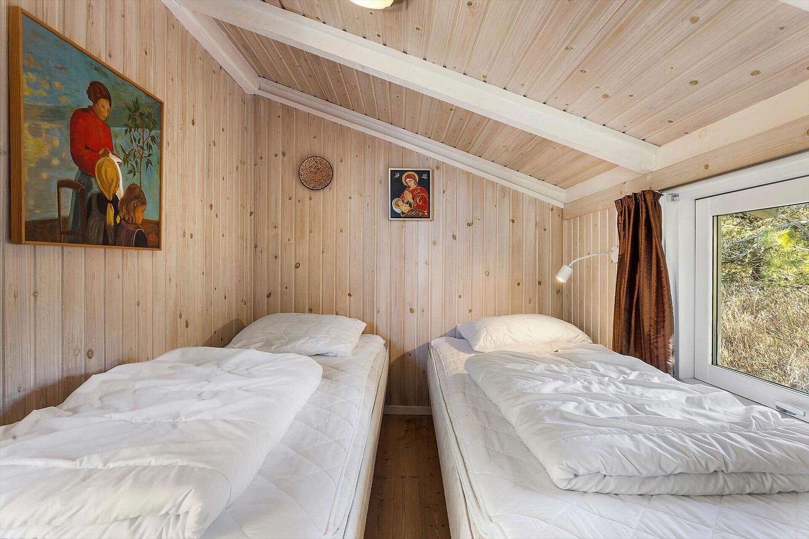 Zwei Betten in einem Holzraum mit Fenster und Wandbildern.
