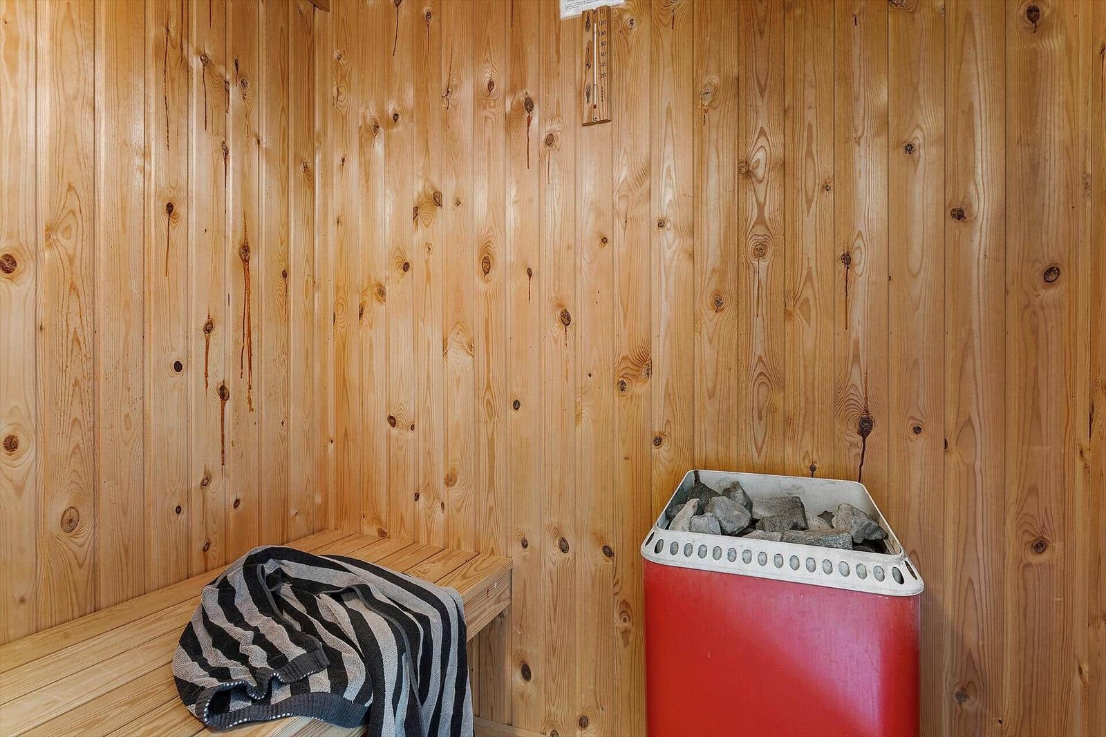 Sauna mit Holzwand, Bank und Steinkiste.