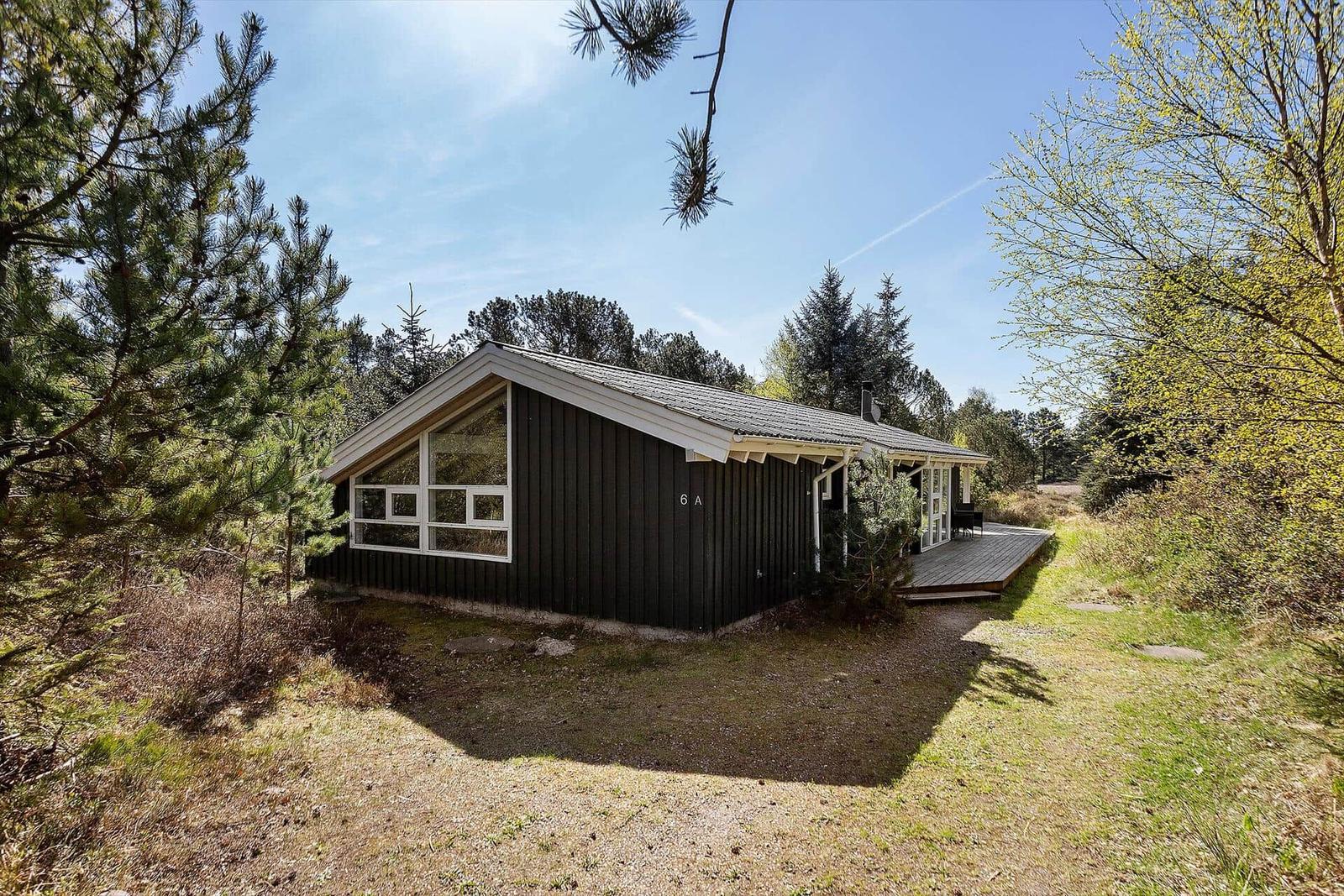 Holzhütte mit Terrasse und großem Fenster im Wald