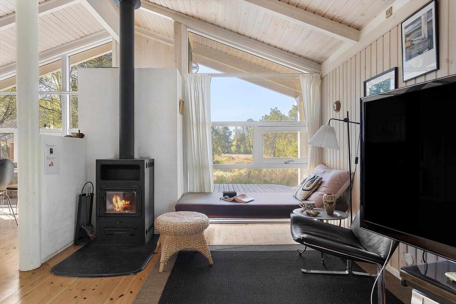 Wohnraum mit Kamin, Fensterblick und Sitzgelegenheit.