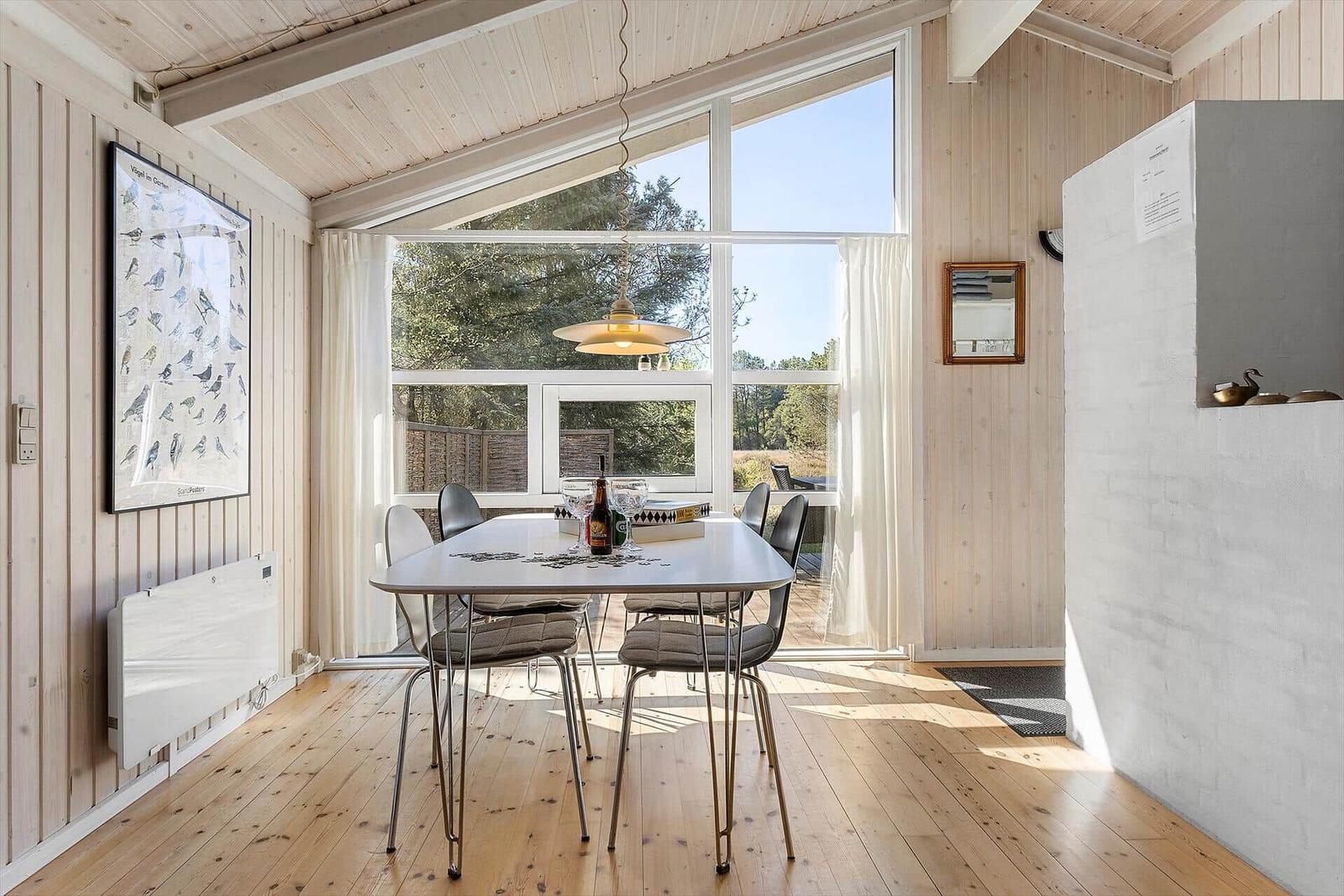 Esszimmer mit Tisch, Stühlen und großem Fenster zur Außenseite.