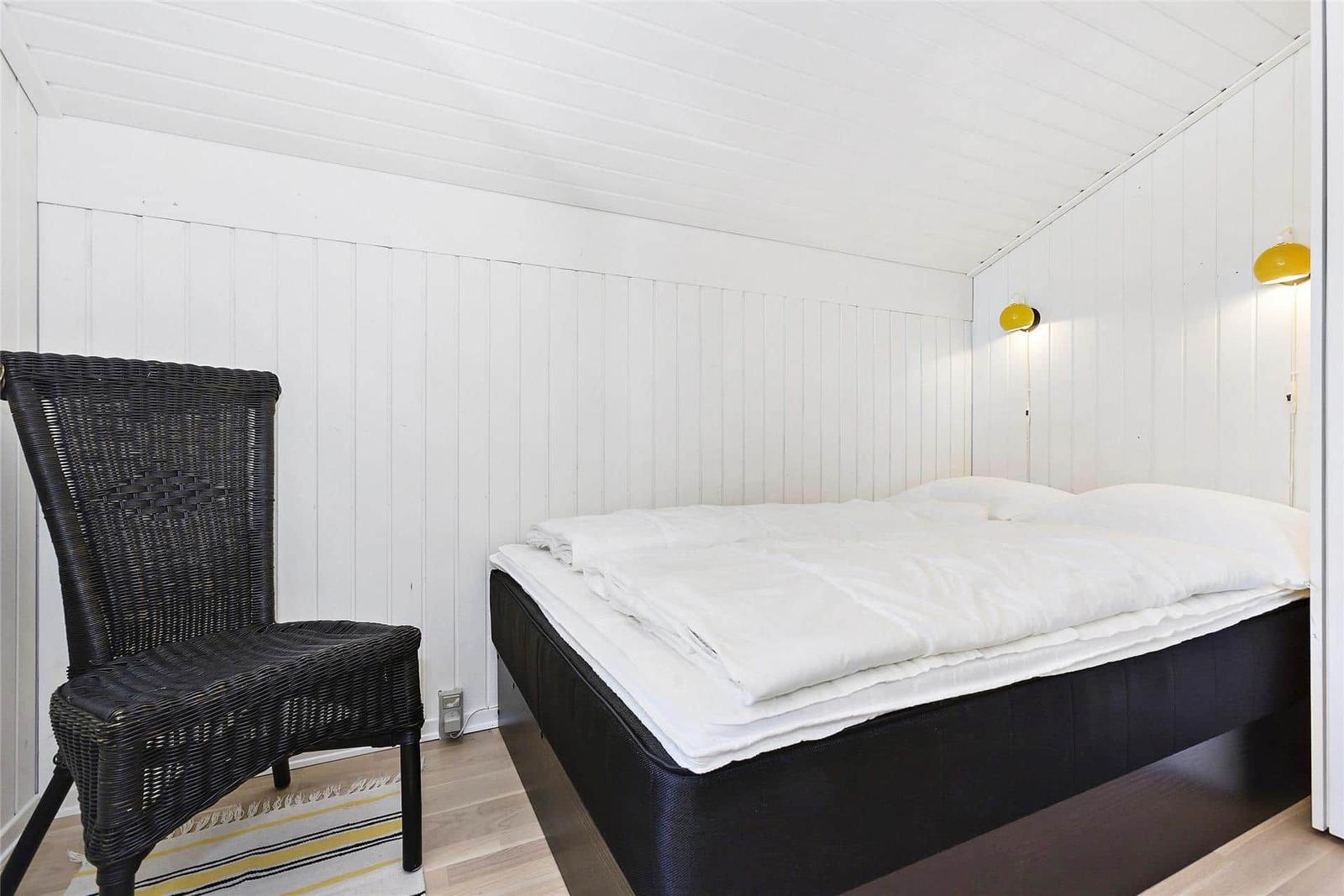 Schlafzimmer mit Bett, Stuhl und Wandlampen.