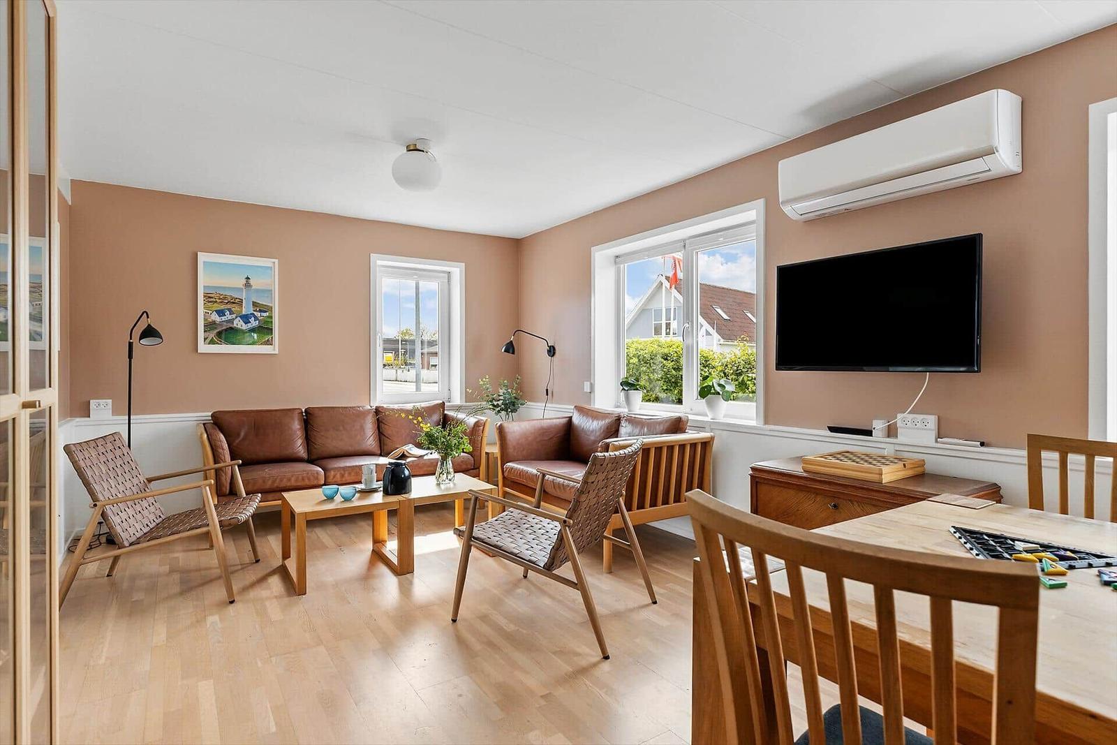 Wohnzimmer mit Sofa, Stühlen, Fernseher und Blick auf Garten.