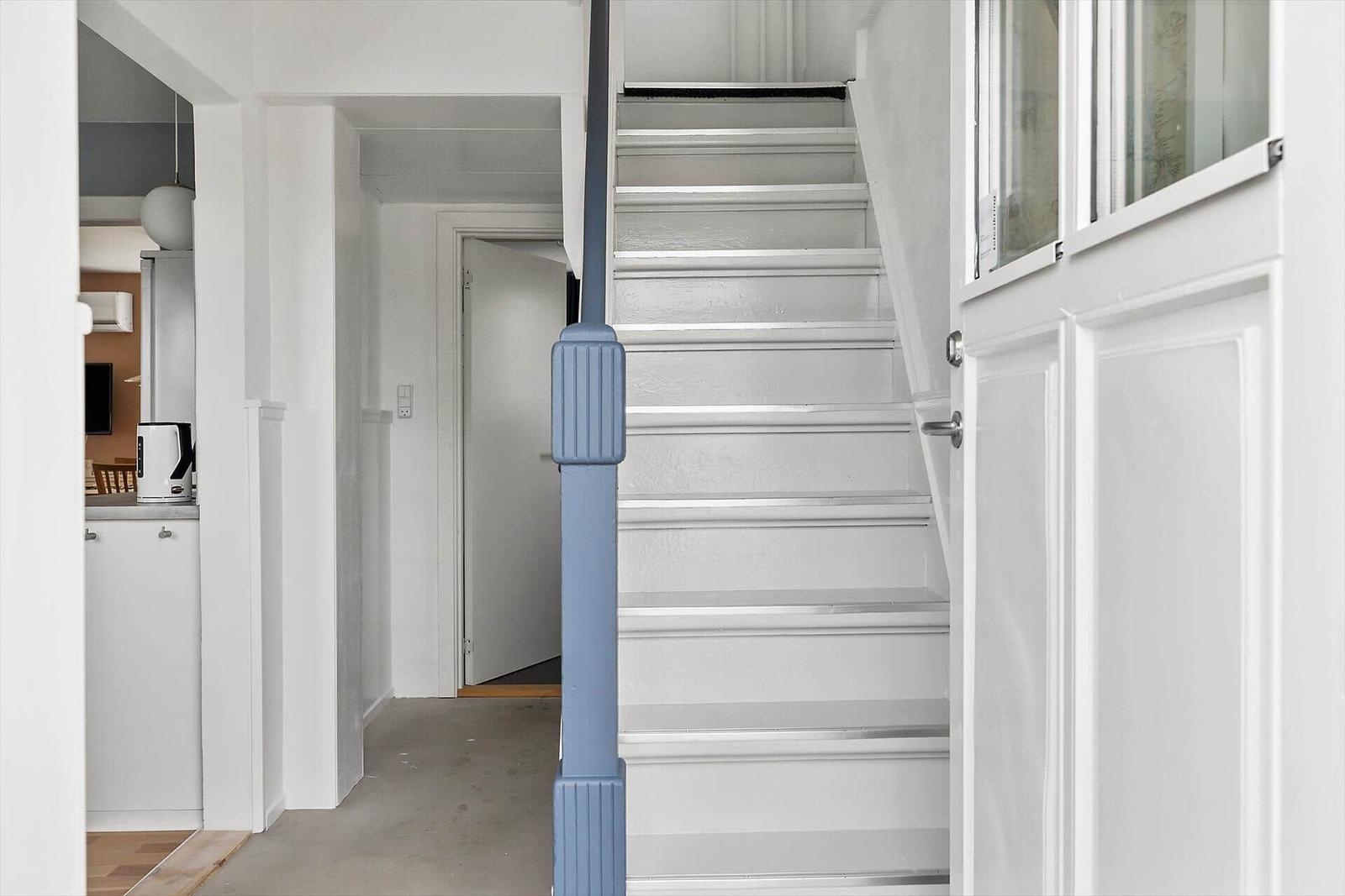 Treppenhaus mit blauer Stütze und weißen Stufen führt zur oberen Etage.