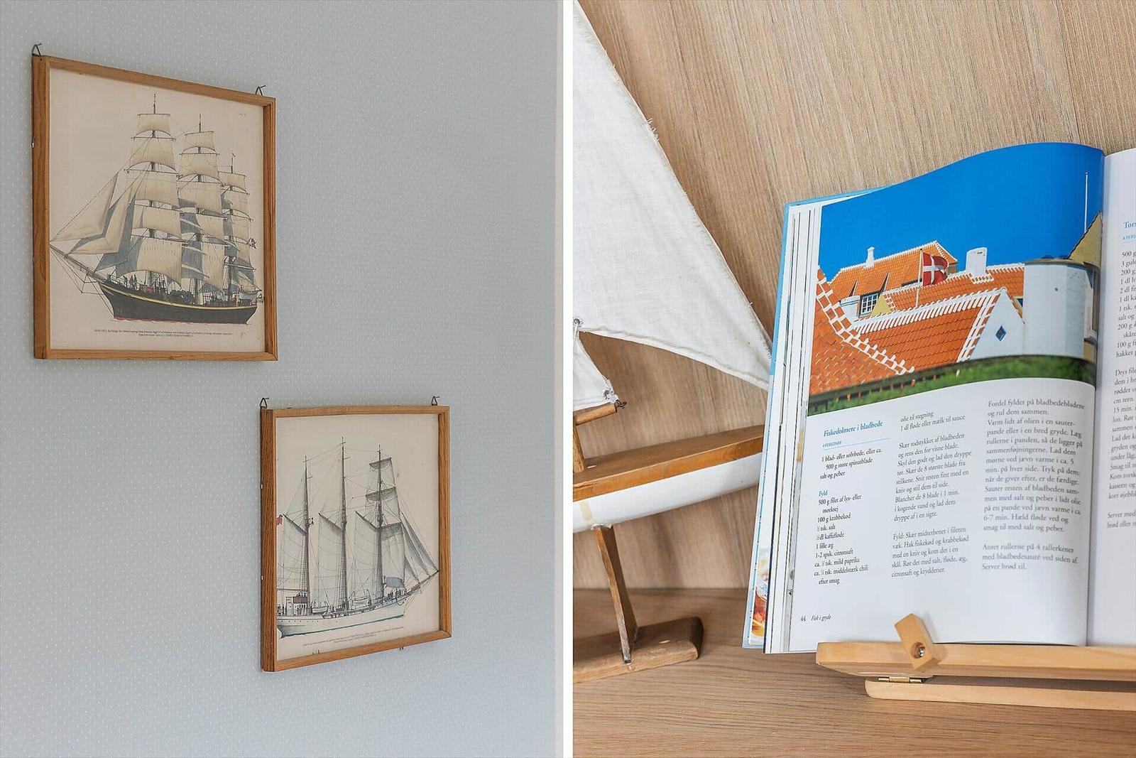 Wand mit zwei Schiffsbildern und Tisch mit Buch und Modellboot.