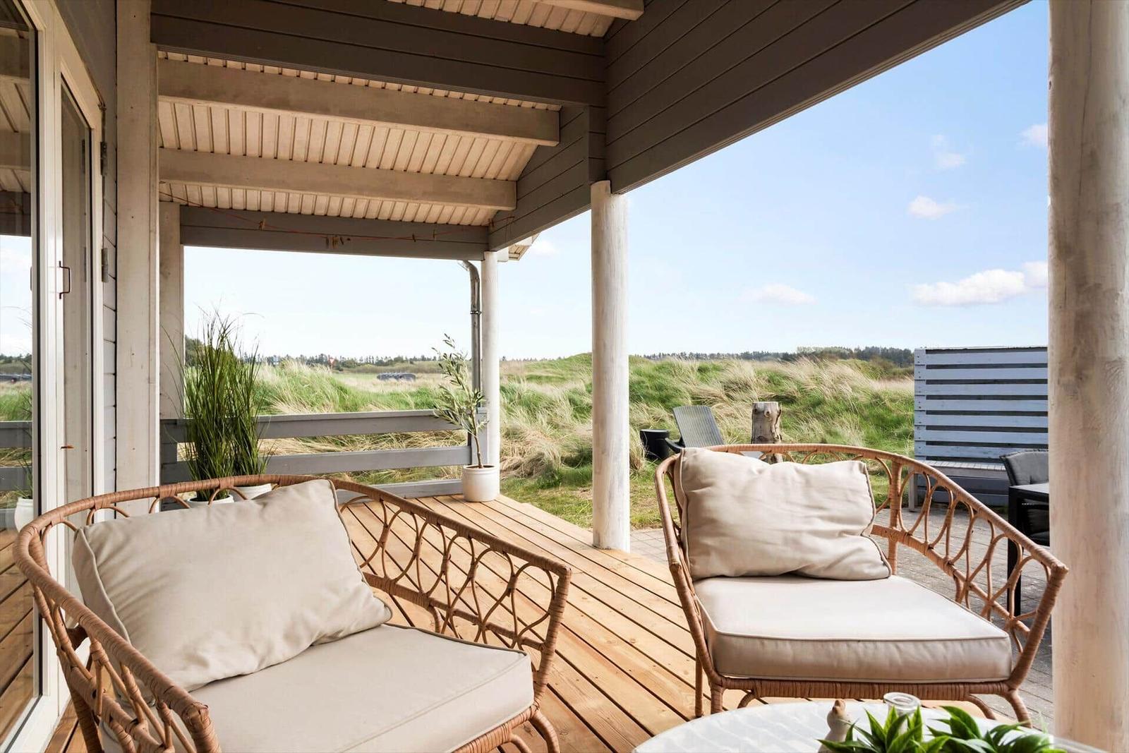 Terrace with two wicker chairs and view of grassland.
