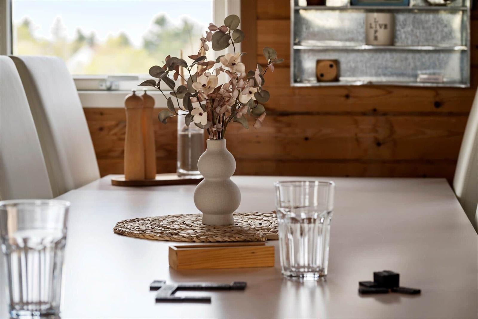 Table with vase, glasses, and decor against wooden wall