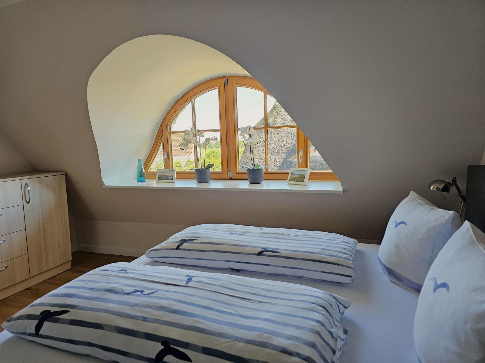 Schlafzimmer mit Dachschräge, Fenster und Bett