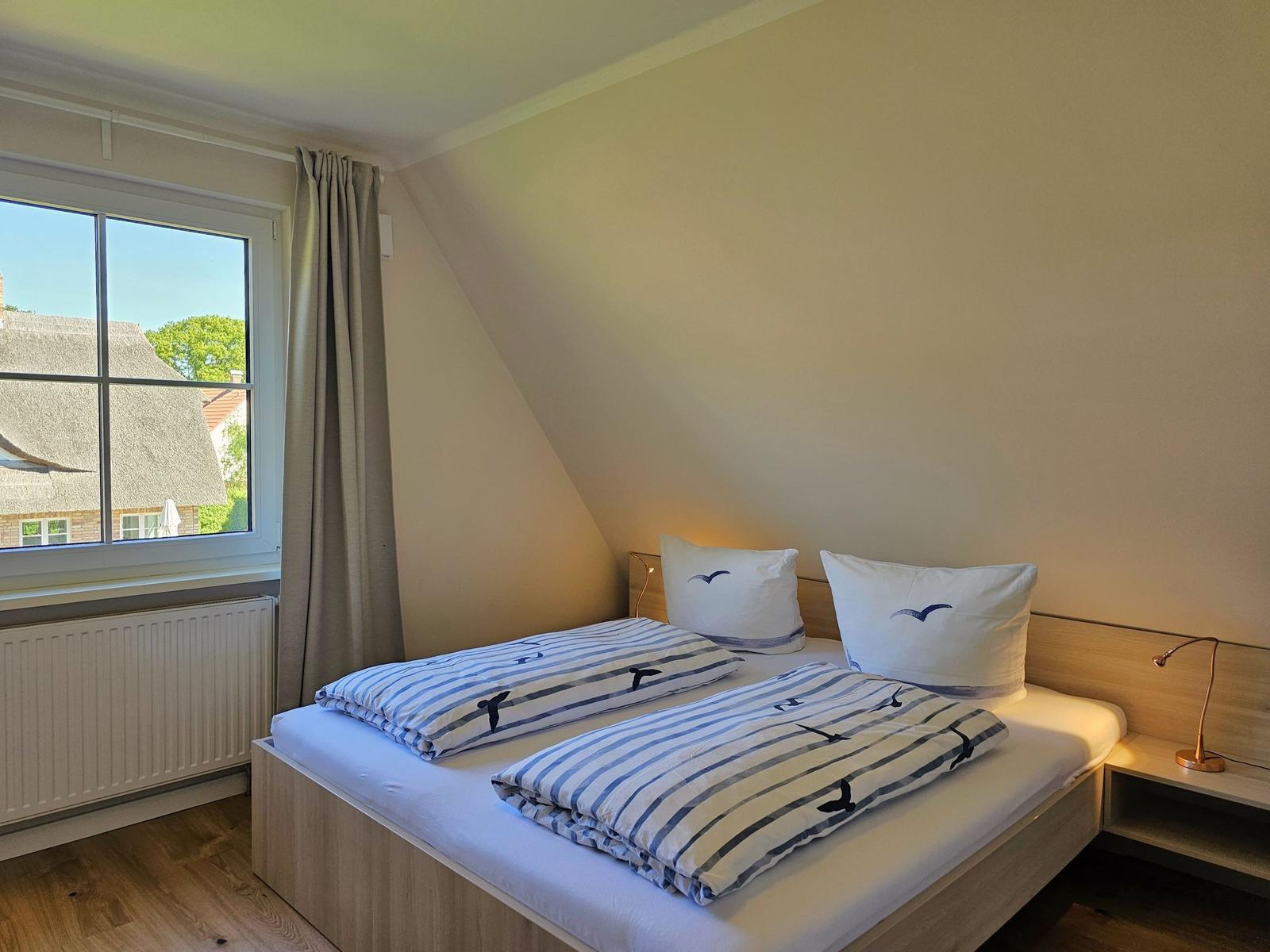 Schlafzimmer mit Doppelbett, Fenster und Schreibtisch