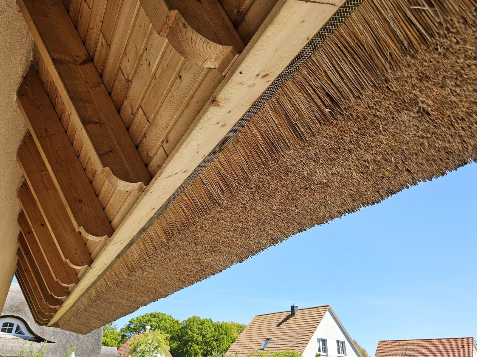 Dach mit Stroh und Holzkonstruktion unter blauem Himmel
