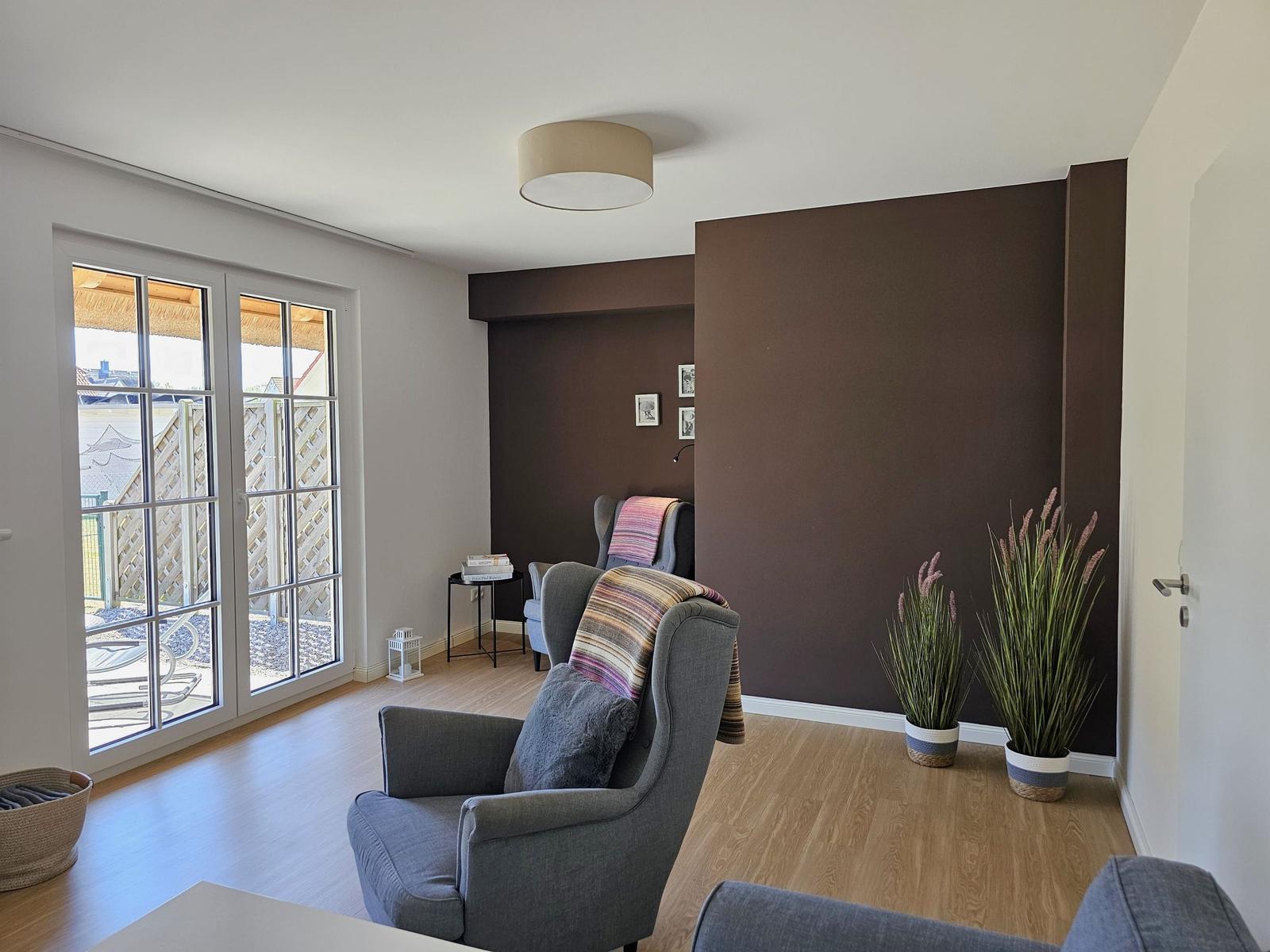 Wohnzimmer mit Sitzgelegenheiten, Pflanzen und Blick auf die Terrasse.