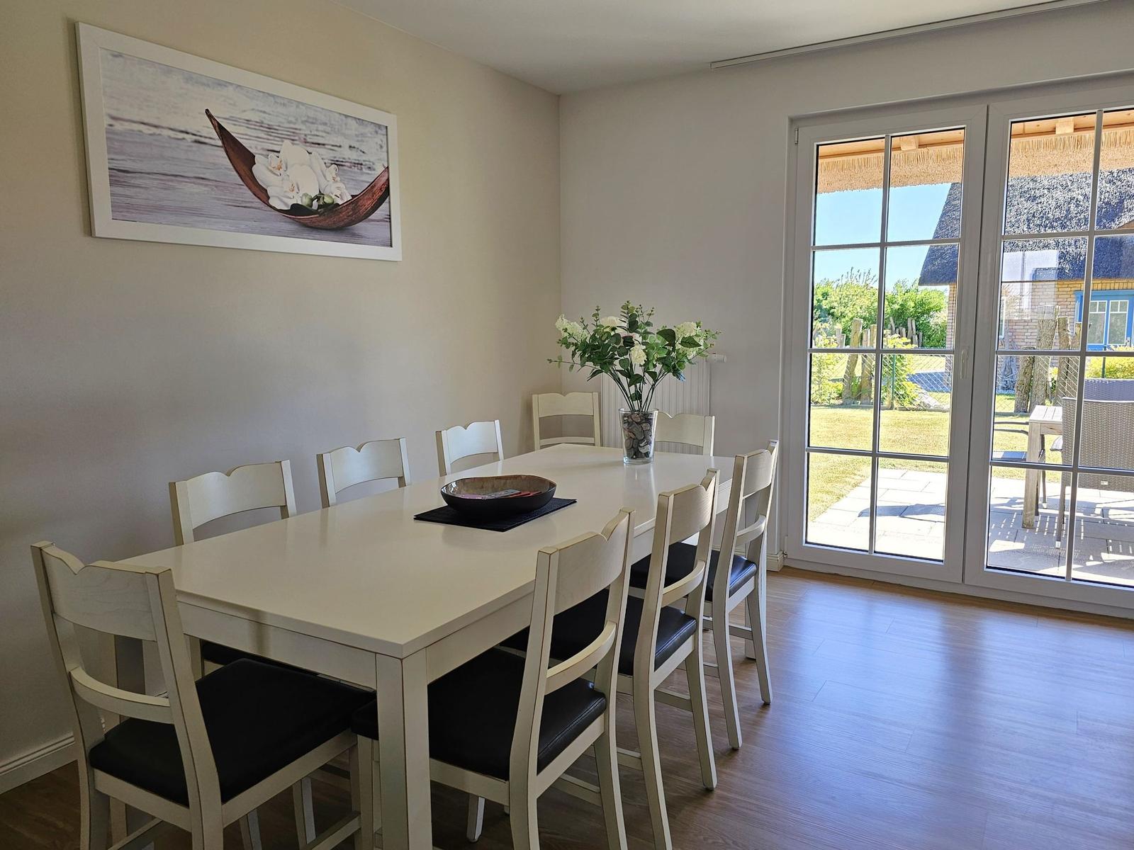 Esszimmer mit Tisch, Stühlen und Blick auf die Terrasse.