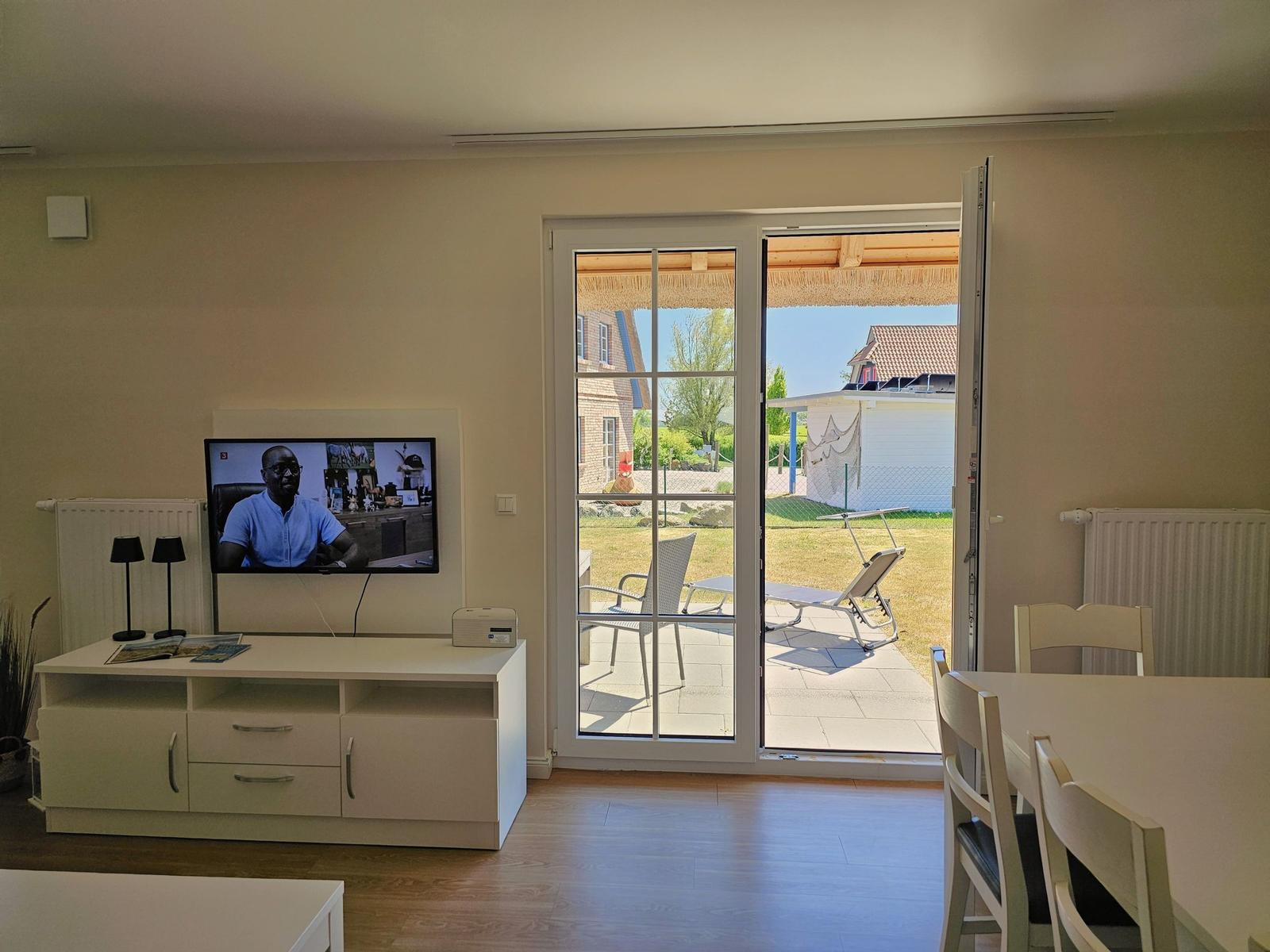 Wohnzimmer mit TV, Esstisch und Blick auf die Terrasse.