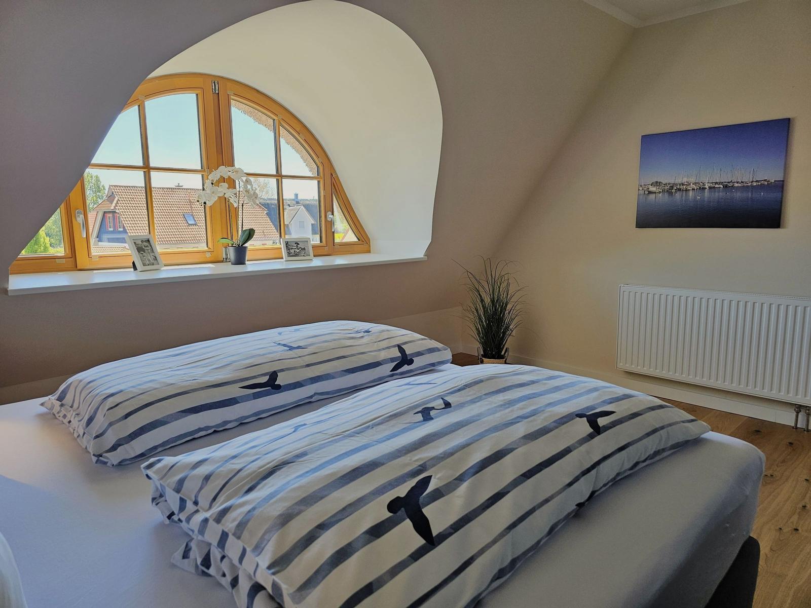 Schlafzimmer mit Bett, Fenster und Wandbild