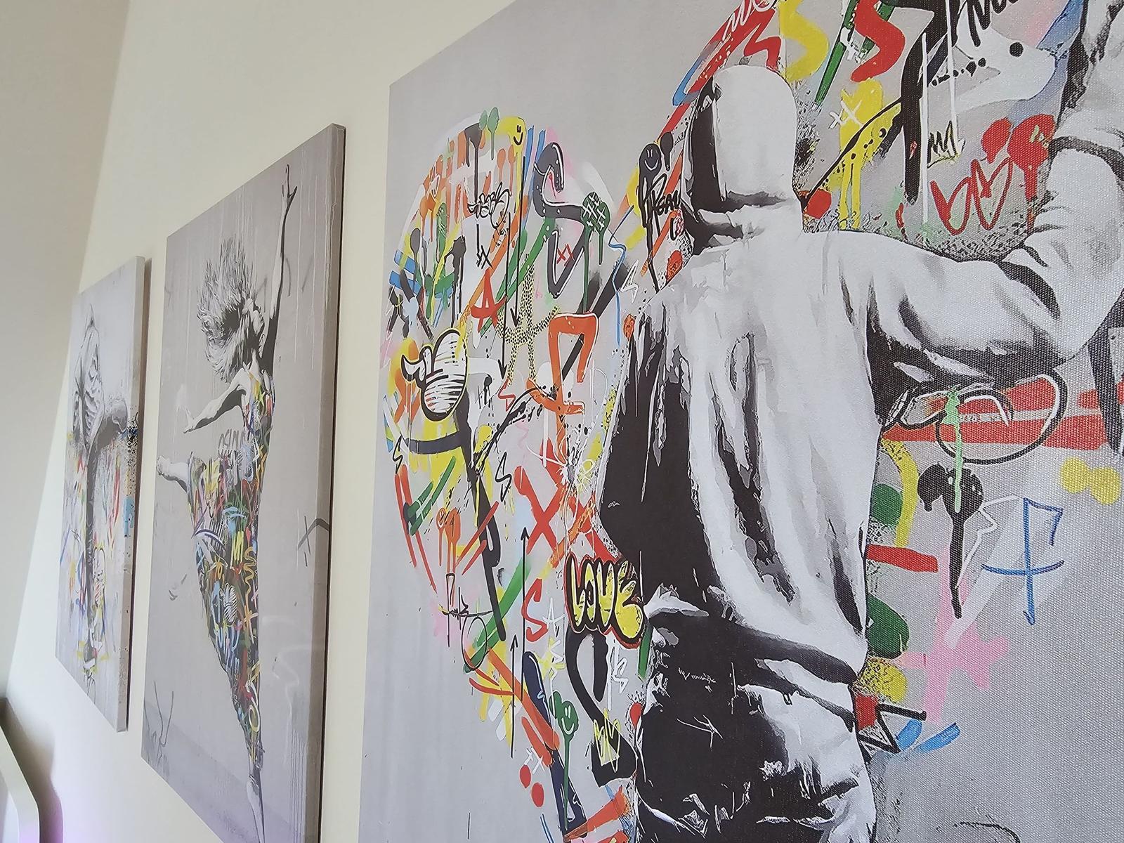 Wand mit drei modernen Kunstwerken, eins mit Graffiti-Elementen.
