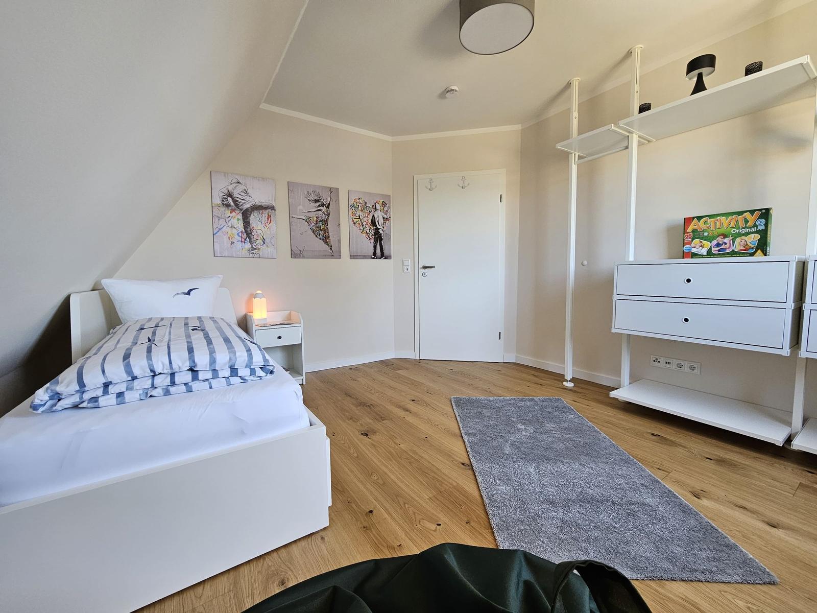 Schlafzimmer mit Bett, Schrank und Wandbildern.