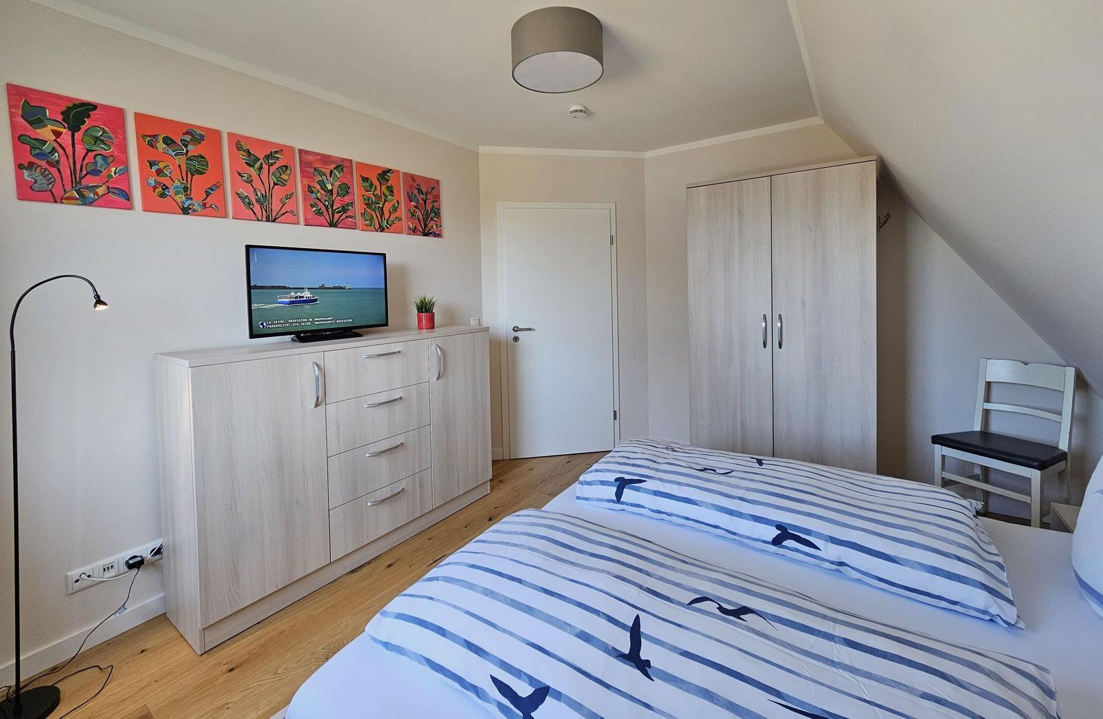 Schlafzimmer mit Bett, Kleiderschrank und TV. Wandbild und Holzboden.