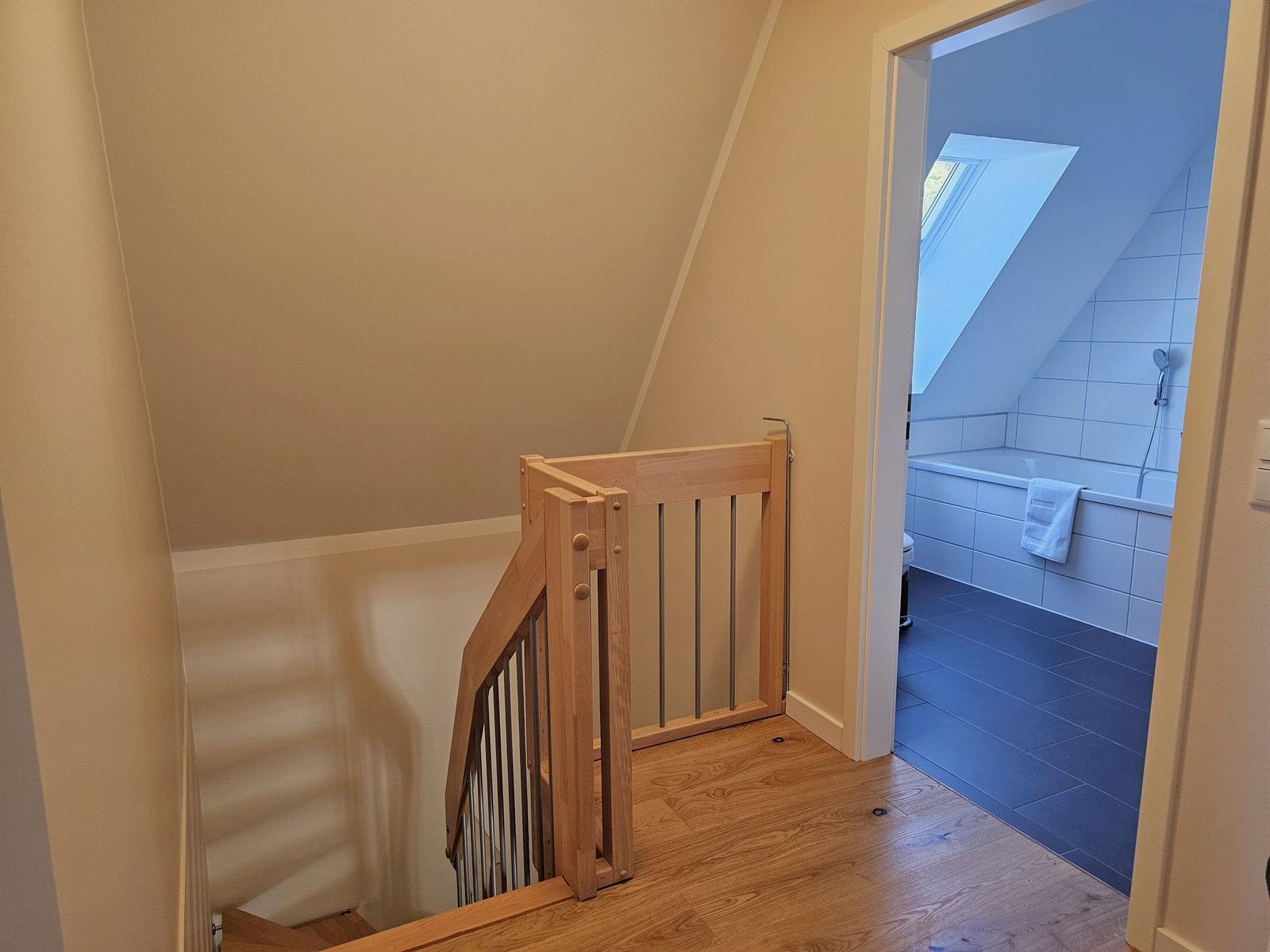 Treppenhaus mit Holzgeländer und Blick in die Dusche.