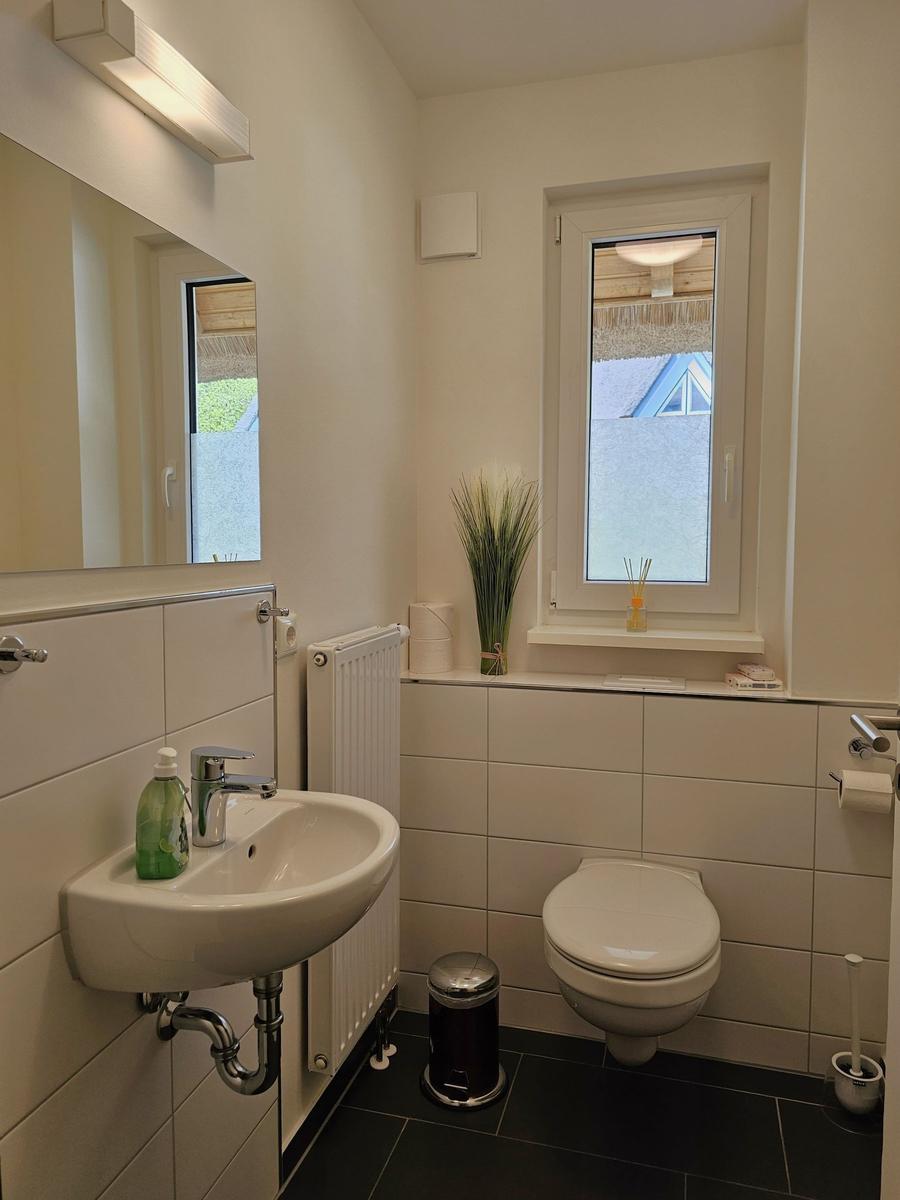 Badezimmer mit Waschbecken, Toilette und Fenster
