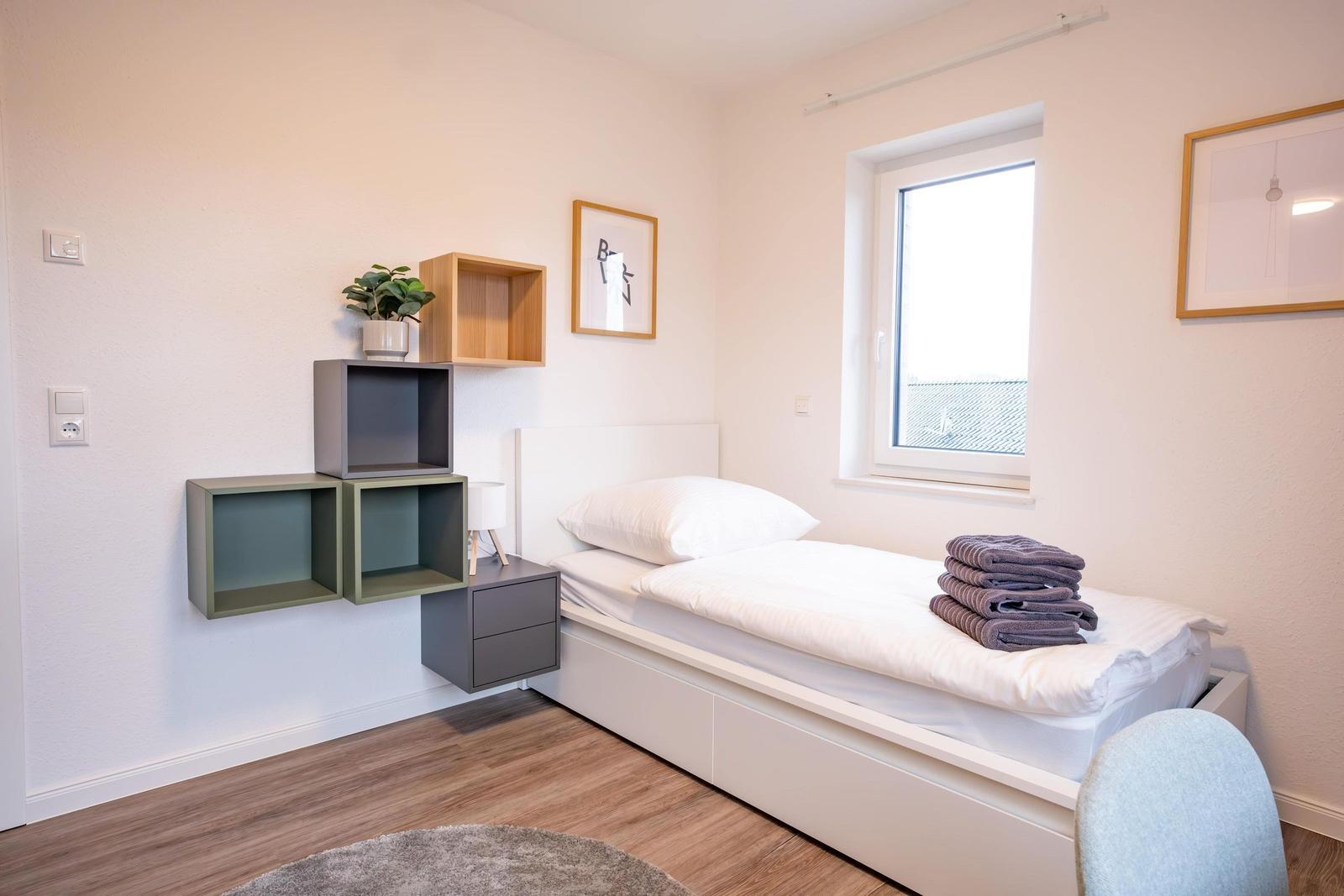 Ein Schlafzimmer mit Bett, Wandregalen und Fenster.