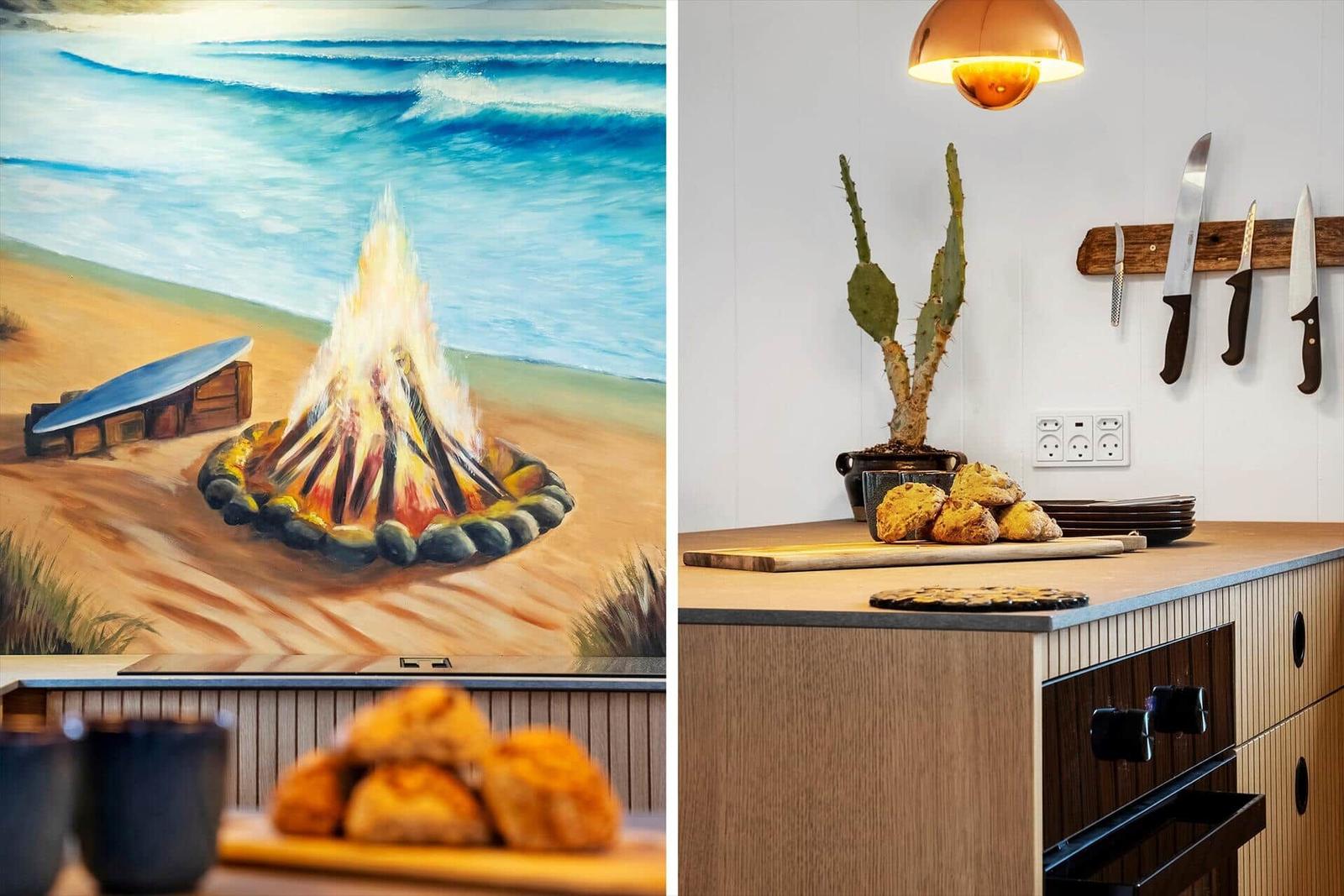 Küche mit Holzoberfläche, Kaktus und Küchenutensilien. Wandbild zeigt Strand mit Lagerfeuer.