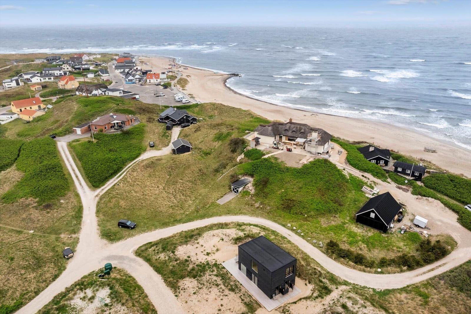 Aerial view of coastal property with houses, dunes, and beach.