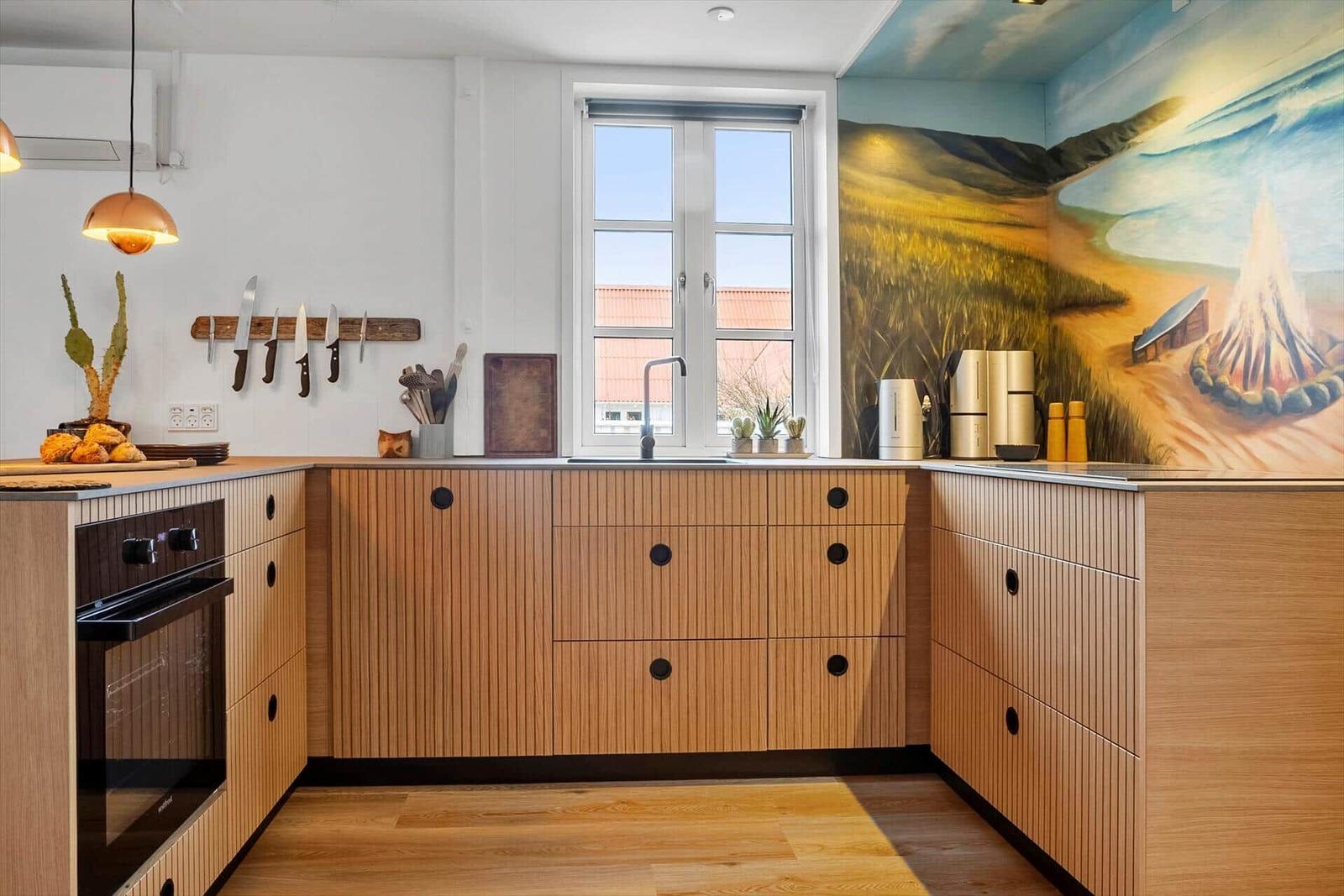 Küche mit Holzschränken, Fenster und Wandmalerei