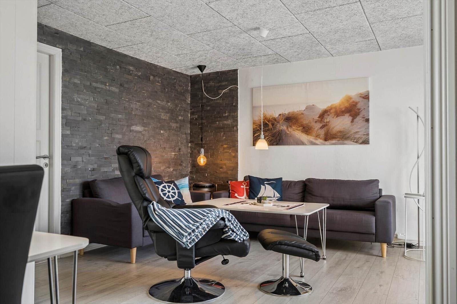 Wohnzimmer mit Sofa, Sessel und Wandbild