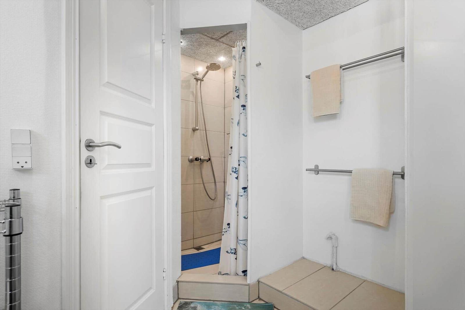 Badezimmer mit Dusche, Handtuchhalter und Tür.