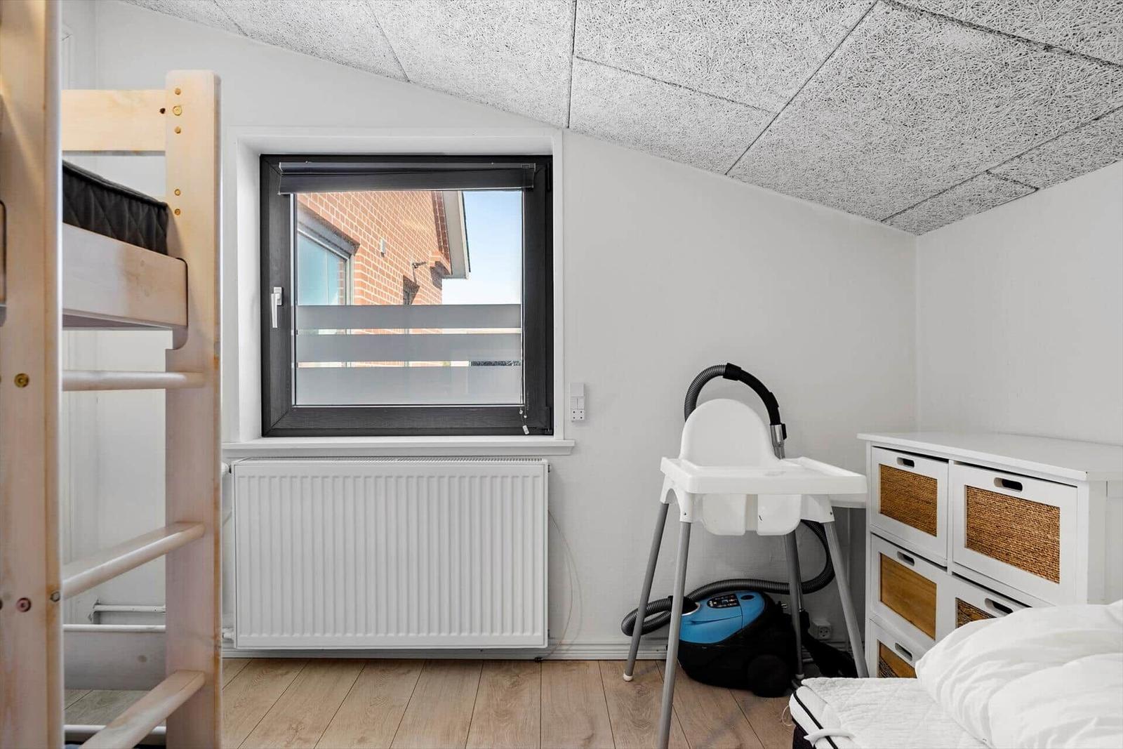 Zimmer mit Babyhochstuhl, Krippe und Fenster mit Blick.