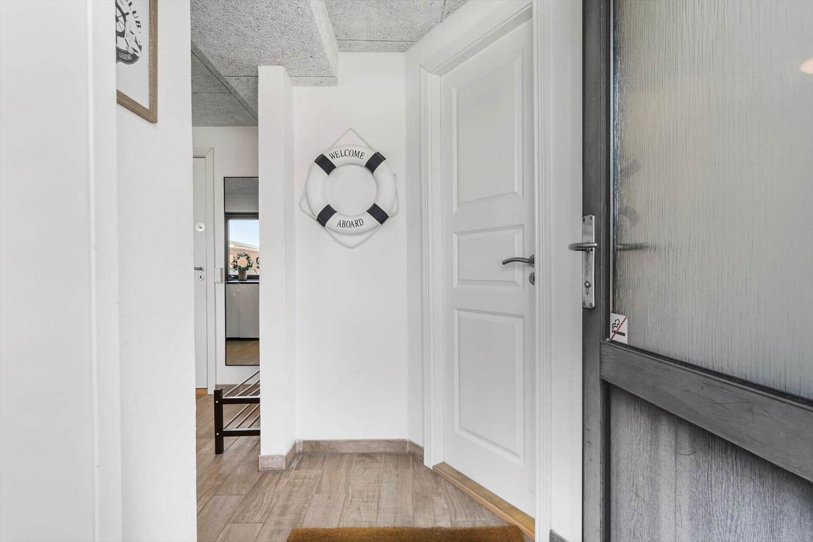 Hausgang mit weißen Wänden, Holzboden und Rettungsring an der Wand.