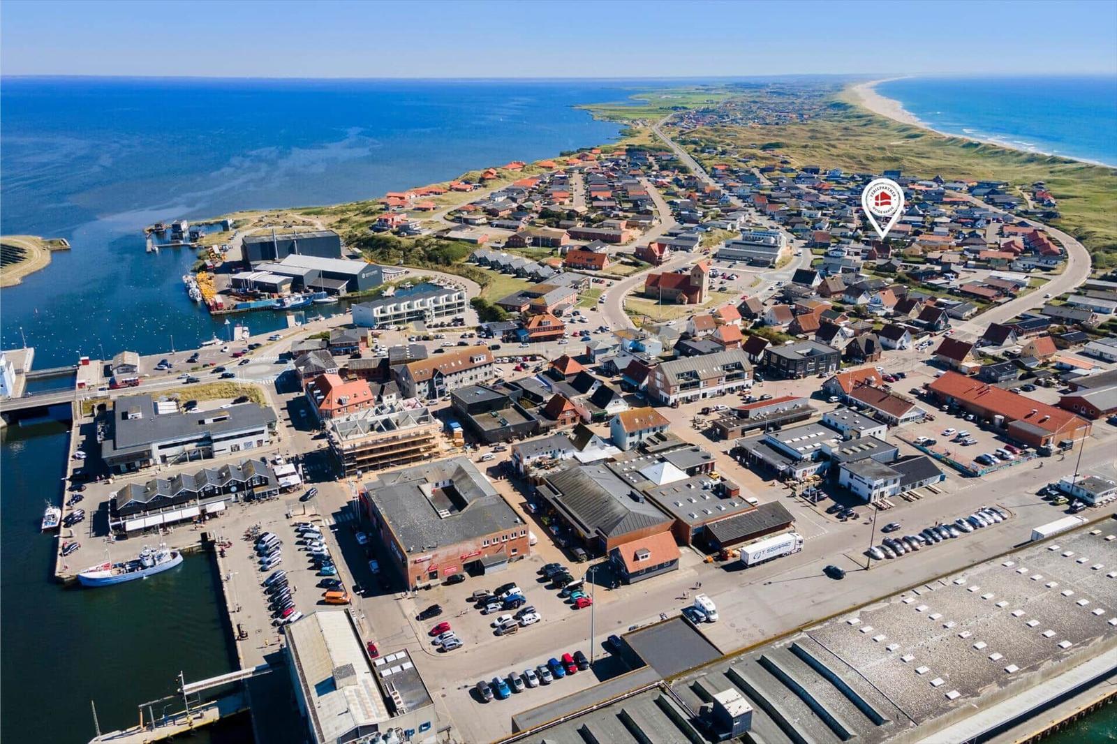 Aerial view of coastal town with harbor, beaches, and residential areas.