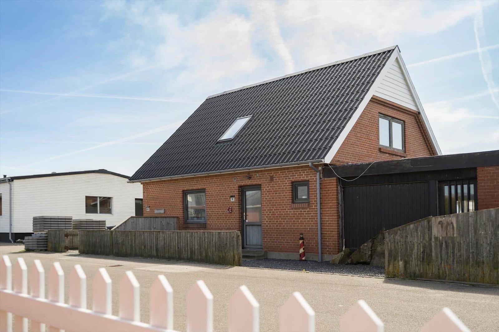 Moderne Ein-Familienhaus mit rotem Backstein, schwarzem Dach und Holzgarage.