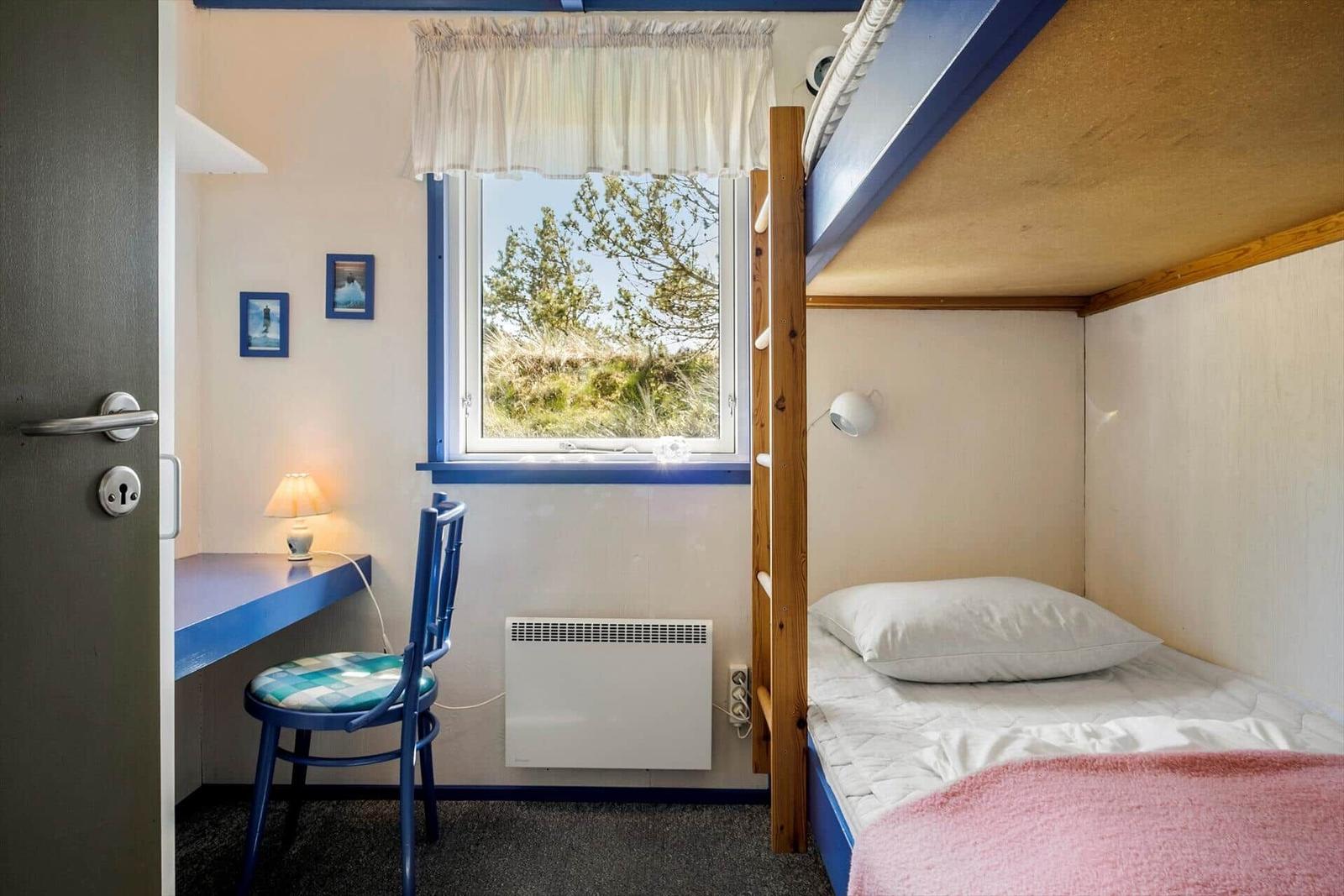 Zimmer mit Doppelstockbett, Schreibtisch und Fenster mit Blick auf Grünflächen.