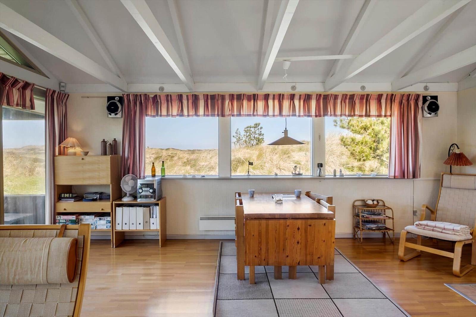 Raum mit Essbereich, Fenster zur Dünung und Holzmöbel.