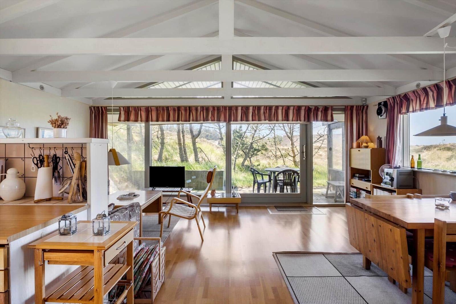 Wohn- und Essbereich mit Holzboden und großem Fensterblick auf Garten.