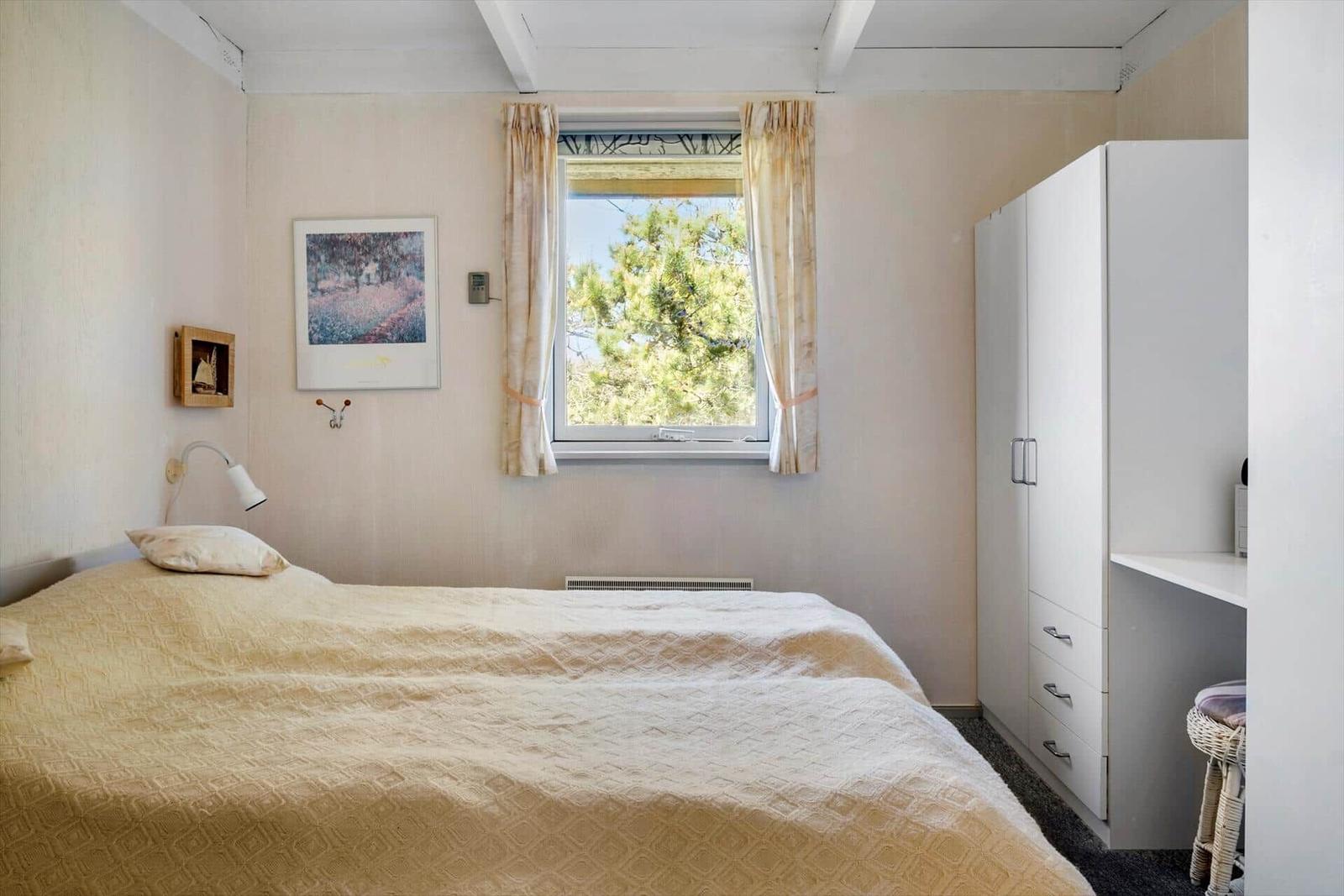 Schlafzimmer mit Bett, Fenster und Kleiderschrank