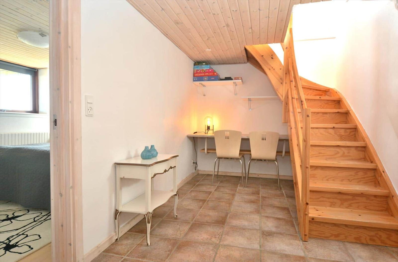 Hölzerner Treppenaufgang, Schreibtisch mit zwei Stühlen und kleiner Tisch.