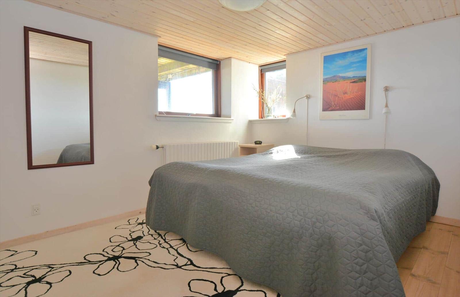 Schlafzimmer mit Bett, Wandspiegel und Fenstern
