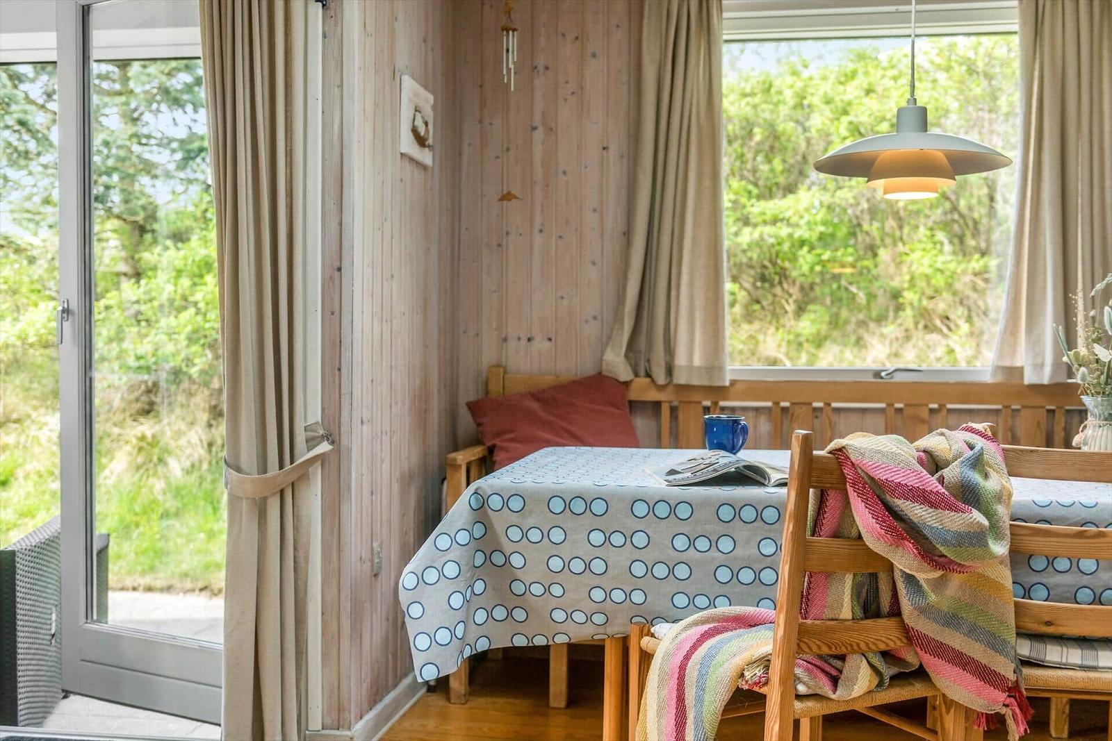 Essbereich mit Holztisch, Stühlen und Fensterblick auf Grün.