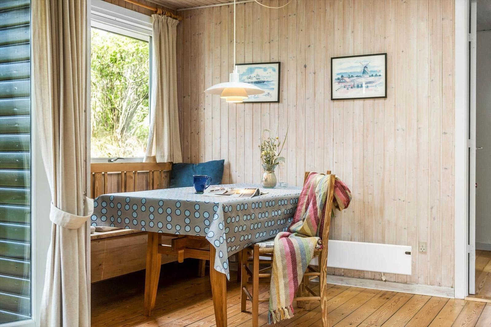 Essbereich mit Holzwand, Tisch, Stühle und Fenster mit Blick auf Grün.