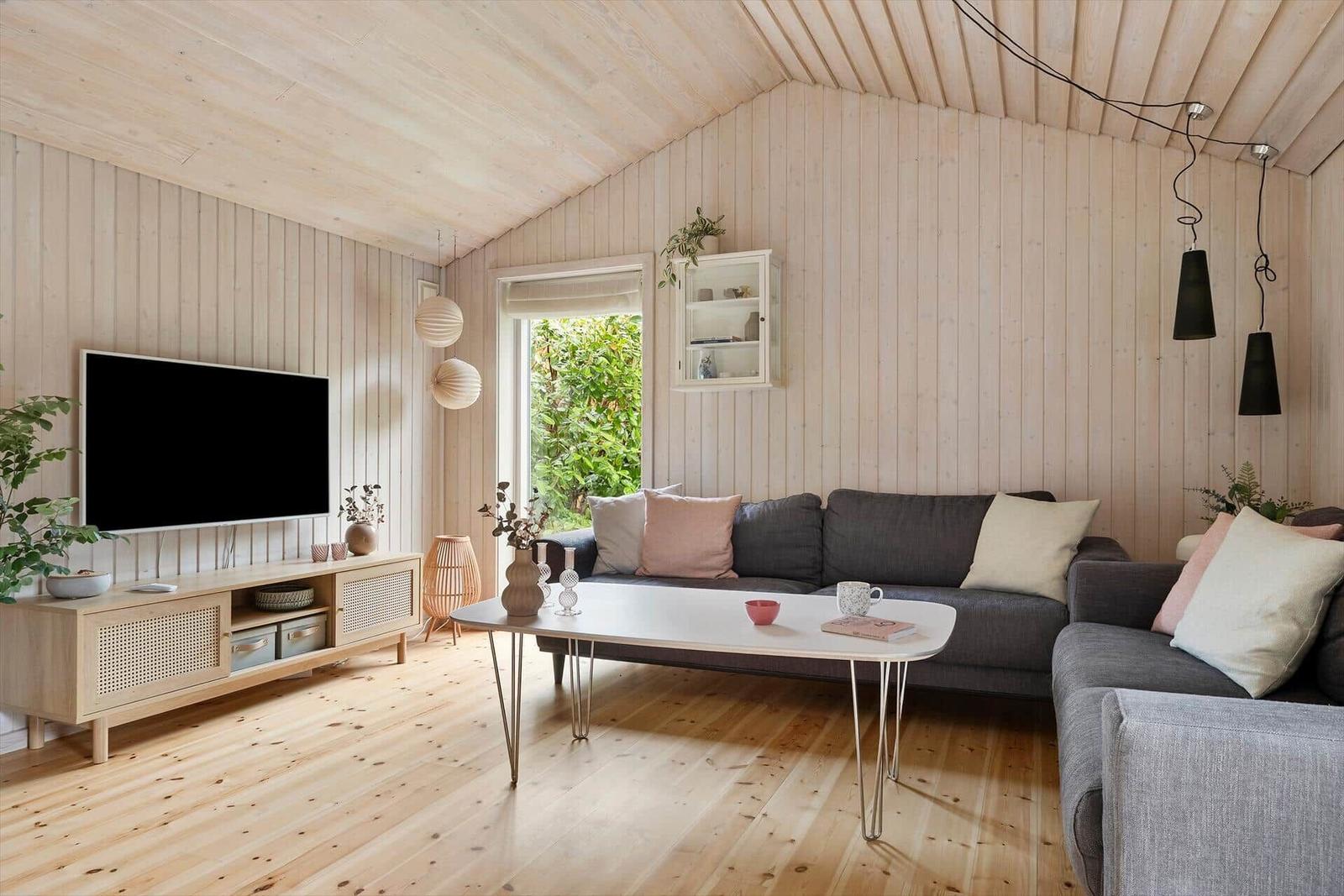 Wohnzimmer mit Holzwand, Sofa, Fernseher und Tisch.